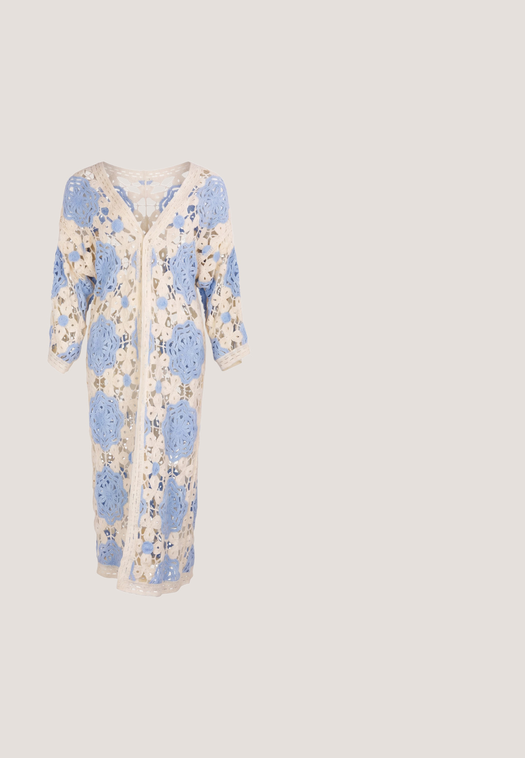 Lang beige hæklejakke med store blå blomsterprint, åben strikket design, V-hals og lange ærmer.; Ærmeløs cremefarvet hæklet top med blomsterudskæringer og lange frynser langs kanten.; Hvid, lagdelt maxiskørt lavet af let, struktureret stof med elastisk talje. Har tre forskellige stofsektioner.; Taupe ruskindsankelstøvle med udsparingsmønster, afrundet tå og lavt træhæl. Lynlåsdetalje på siden, sommerfugleaccent på hælen.; Brun ruskind crossbody taske med lange frynser og en matchende lille pung, begge med guldfarvet hardware.; Guldtonet halskæde med små, strukturerede led. Har to vedhæng: en glat skalformet og en hamret cirkulær form.