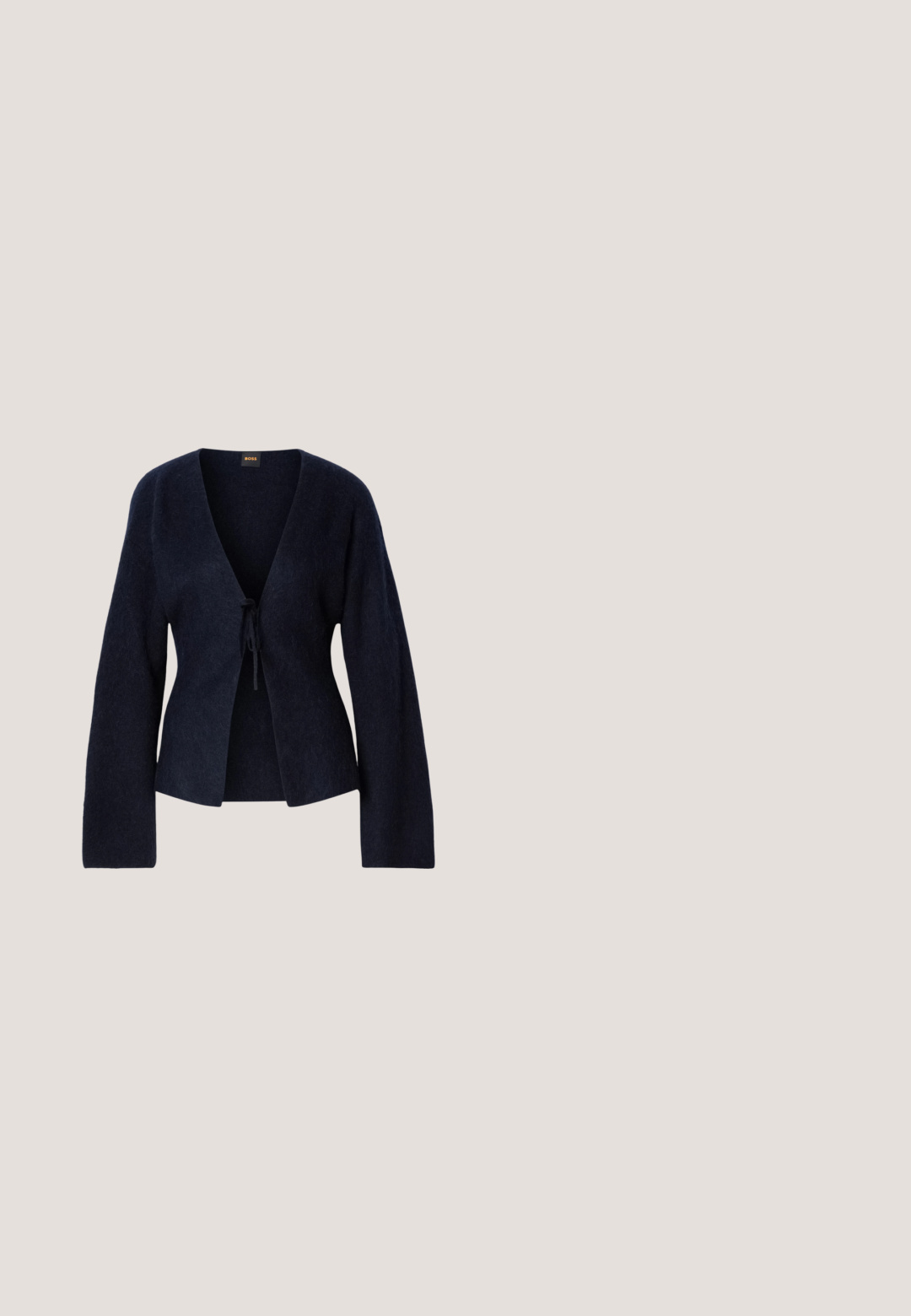 Cárdigan largo de manga larga en azul marino, fabricado en un tejido suave, con escote en V y un cierre de lazo en la parte frontal, que presenta un acabado ligeramente texturizado.; Camiseta sin mangas blanca de algodón, con un diseño sencillo que presenta un escote redondo y el logo negro "HUGO" en el centro. Textura suave.; Jeans de mezclilla de pernera ancha en un acabado azul oscuro, con cintura alta, cierre delantero con botón y diseño clásico de cinco bolsillos. Textura suave.; Zapato slingback de piel negra con puntera puntiaguda, tacón alto y ancho, y forro interior beige sobre un fondo claro y liso.; Bolso pequeño de color crema con forma curva y asa de cadena trenzada en tono dorado, cierre con cremallera en la parte superior; Pendientes largos de oro compuestos por cuatro barras curvadas enlazadas y alargadas sobre un fondo blanco.