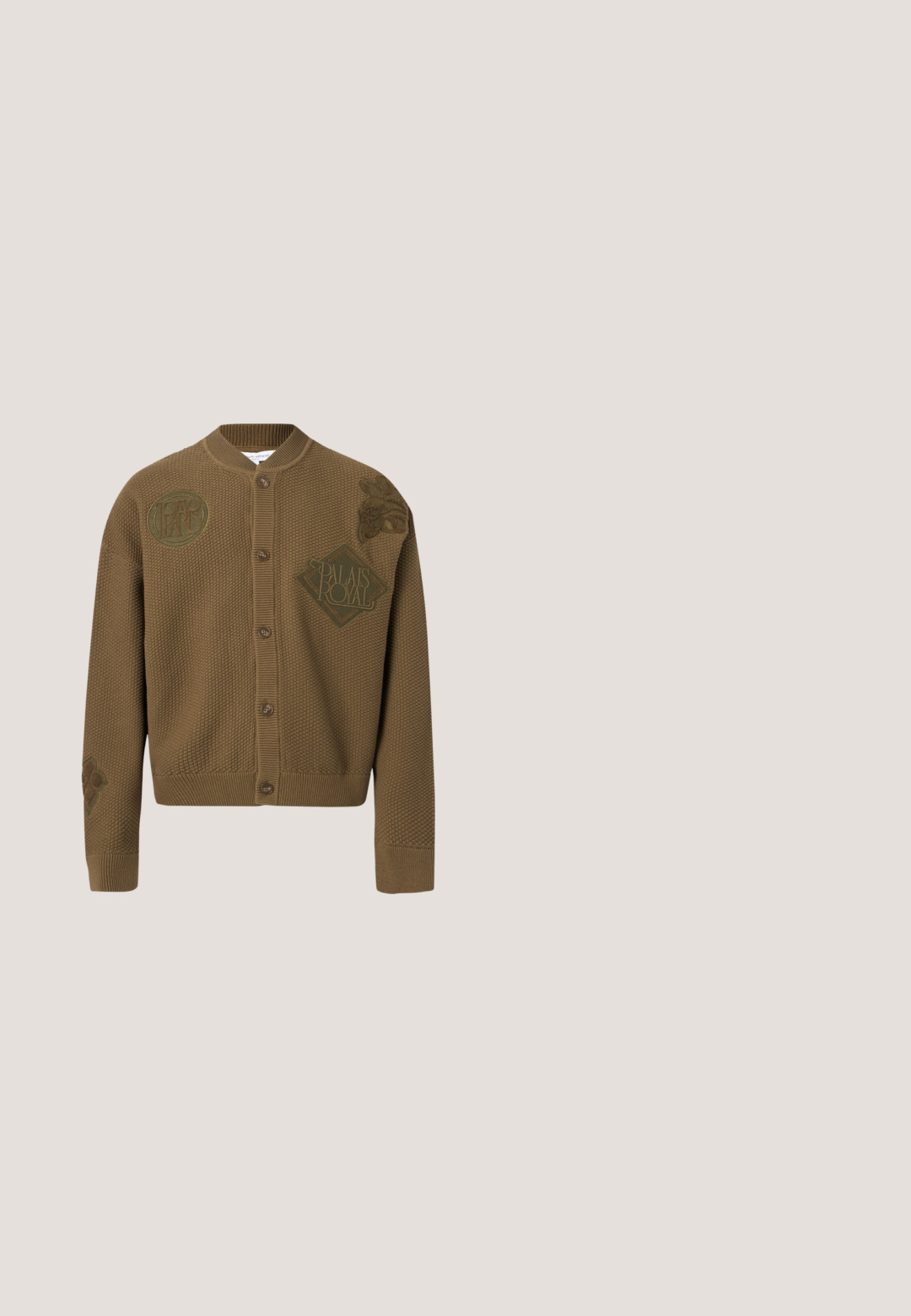 Brun tekstureret cardigan med knapper, ribstrikket krave, manchetter og kant, med præget logo "Palais Royal" og blomsterdesigns.; Hvid kortærmet skjorte lavet af tekstureret strikket stof. Har en camp-krave, knaplukning og lodrette striber.; Beige shorts med lodrette brune striber, elastisk linning og justerbar snor. Stoffet virker tekstureret, med et afslappet design.; Sort lædersko i loafer-stil svæver over et beige tæppe med et blankt brunt rundt bord i baggrunden.; Solbriller med sorte stel, rektangulære orangefarvede linser og tynde metalstel, der hviler på en hvid overflade.; Brun læderbælte med en struktureret overflade, der har en metalspænde med en vejrslidt sølvfarve og indgraveret mærkenavn.
