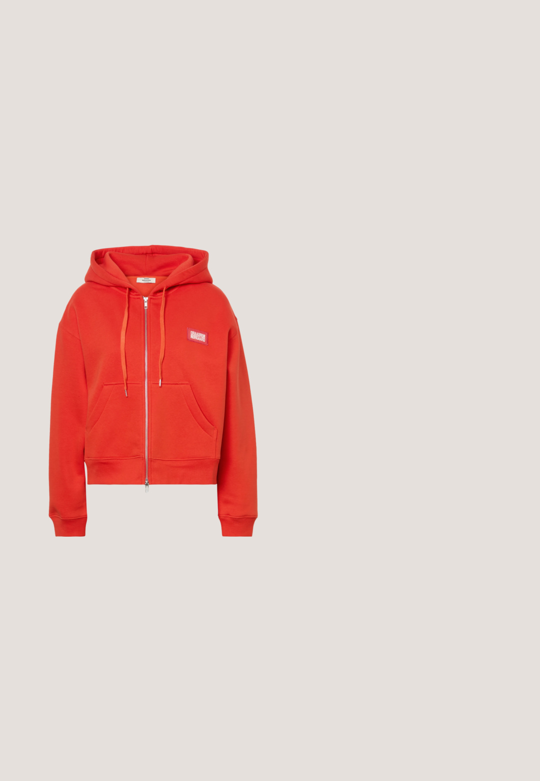 Roter Kapuzenpullover mit Reißverschluss, Fronttaschen, Kapuze mit Kordelzug und kleinem rechteckigem Logoaufnäher auf der linken Brust.; Rotes Baumwoll-T-Shirt mit einem schwarzen grafischen "K"-Design und Streifen auf einem quadratischen Aufnäher. Kurzärmlig und mit Rundhalsausschnitt.; Hellblaue Jeans aus Denim mit hochgekrempelten Säumen, Knopf- und Reißverschluss vorne sowie klassischem Five-Pocket-Design auf weißem Hintergrund.; Weiße Plateausneaker mit glattem Lederobermaterial, rundem Zehenbereich und flachen Schnürsenkeln. Verfügen über eine strukturierte Gummisohle und dezentes Branding an der Seite.; Schwarze Stoff-Tragetasche mit doppelten Griffen und rot gepunkteten abstrakten Mustern, die gleichmäßig auf der Oberfläche verteilt sind, vor einem schlichten Hintergrund.; Kleine goldene Creolen mit rechteckigen Segmenten, jeweils mit einem klaren Edelstein auf der Vorderseite besetzt, mit Ohrsteckerverschluss.