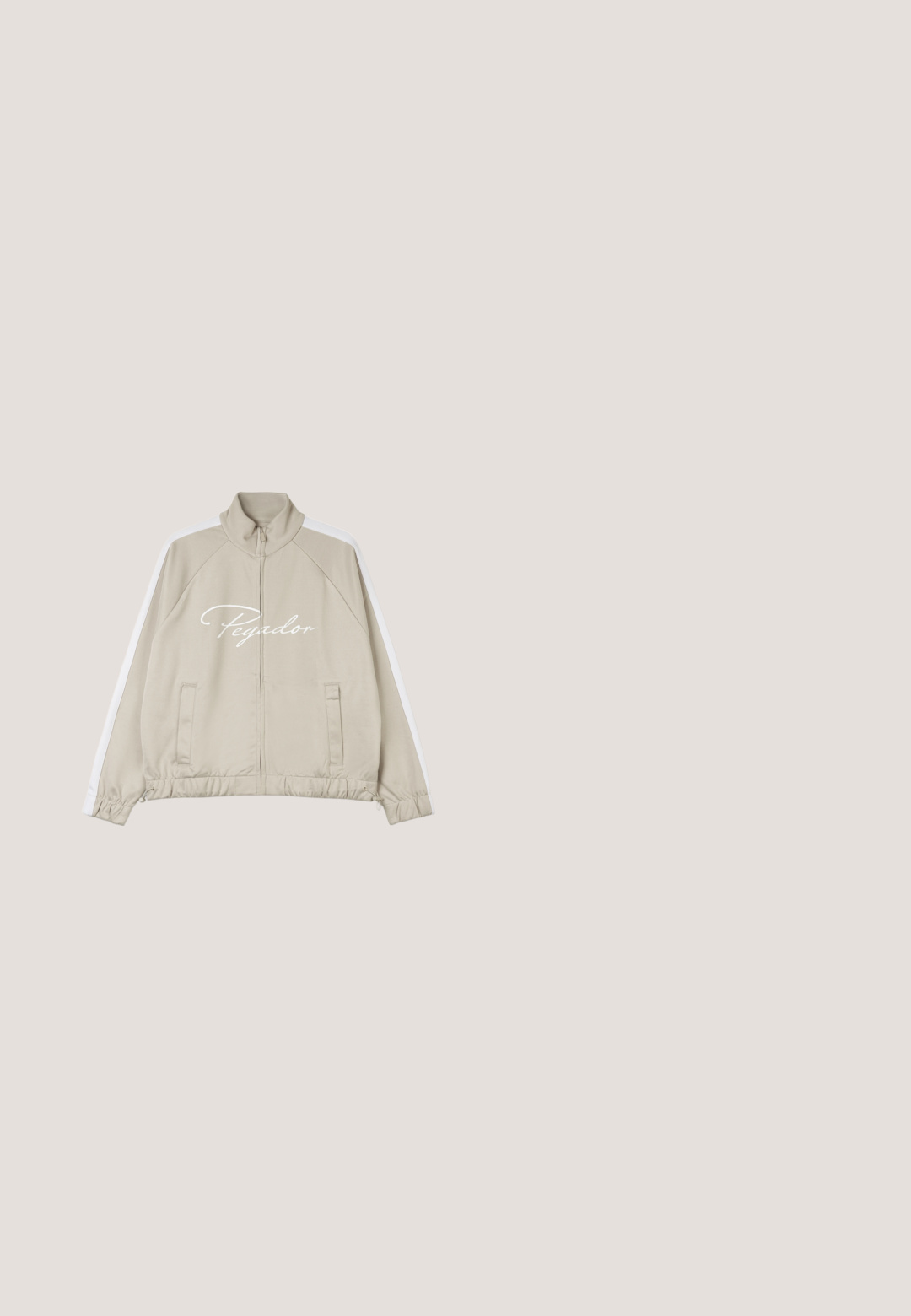 Beige zip-up jas met witte accenten, voorzien van een hoge kraag, elastische manchetten, een trekkoord onderaan en het "Pegador" logo op de voorkant.; Witte katoenen T-shirt met korte mouwen, losse pasvorm, ronde hals en merkembleem aan de binnenkant van de kraag.; Grijze denim jeans met een relaxte pasvorm, voorzien van vijf zakken, subtiele vervaging en een rechte pijpdesign. Classic tailleband met riemlussen.; Lauren Ralph Lauren JANSON II ACTION LEATHER SNEAKER - Sneakers laag - real white; Beige canvas handtas met geborduurd "Coach New York" logo, twee bovenhandvaten, afneembare schouderband en zilverkleurige hardware accenten.; Gevlochten tanleren riem opgerold met zilverkleurige metalen gesp, stiksel detail vlakbij het gespuiteinde op een witte achtergrond.