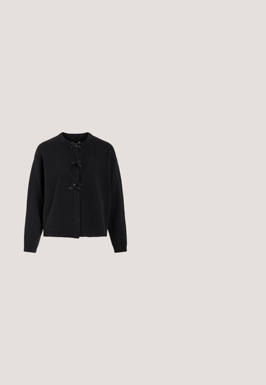Gilet en maille noire avec un col rond et trois boutons décorés de nœuds noirs et de sequins. Coupe décontractée avec des poignets côtelés.; Crop top noir sans manches avec bretelles à volants et accents de volants verticaux au centre devant.; Pantalons pour femmes ajustés gris foncé avec des jambes droites et une fine ceinture assortie dotée d'une boucle dorée.; Chaussure à talon haut en cuir marron foncé à bout pointu, avec bride à la cheville et boucle argentée sur fond blanc.; Sac noir orné de strass étincelants, poignée courbée et fermeture éclair. Comprend des accents de charms, notamment un petit cœur et une silhouette.; Petites boucles d’oreilles créoles en argent avec des breloques en forme de cœur pendentives présentant des bords délicatement perlés et un texte gravé.