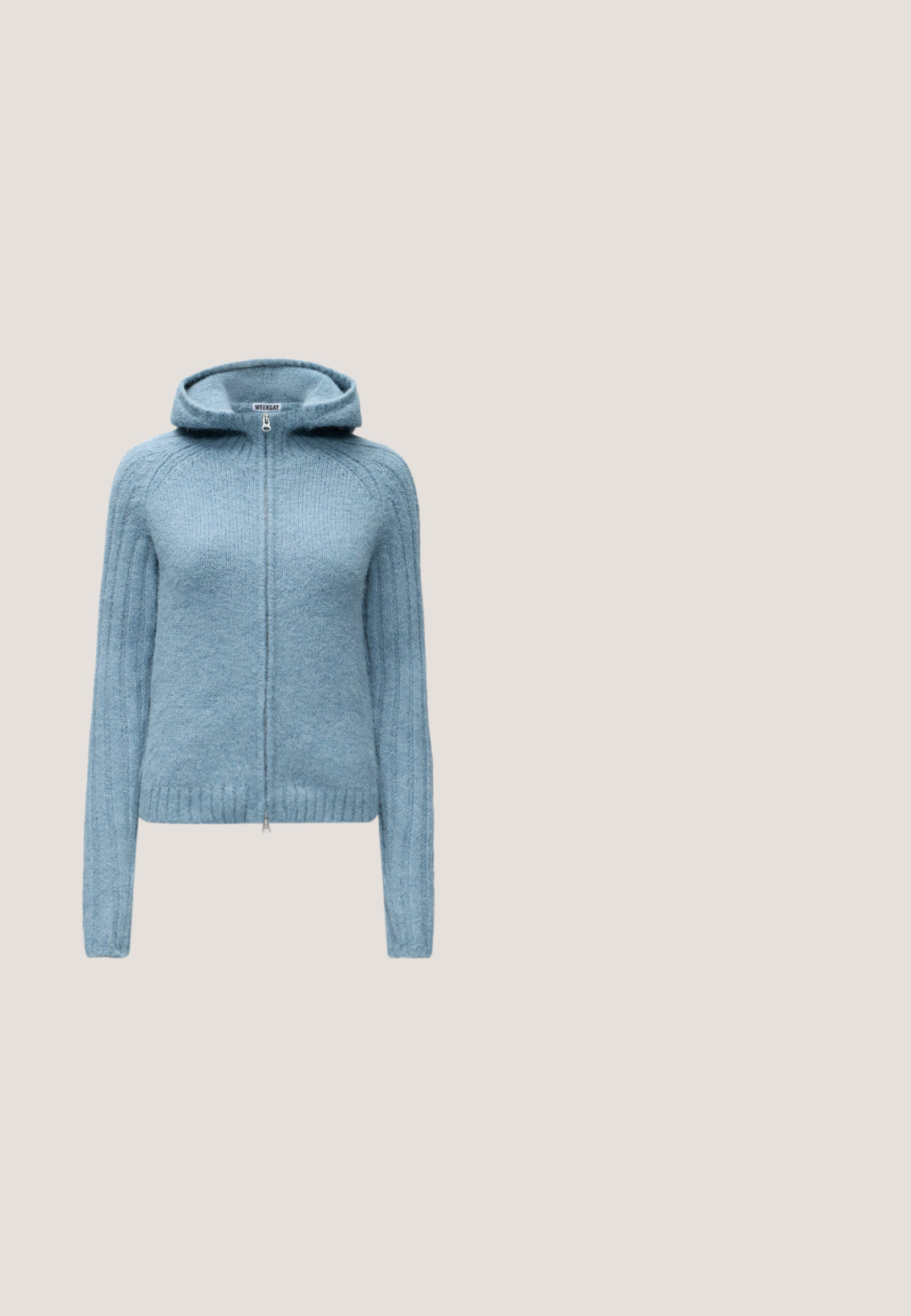 Sweat à capuche zippé tricoté bleu clair avec manches longues et ourlet côtelé, présenté sur un fond uni.; Haut ajusté à manches longues bleu côtelé avec un col rond sur un fond blanc uni.; Pantalon bleu clair droit avec taille élastique, fabriqué en tissu lisse, présenté sur un fond clair uni.; Baskets basses blanches avec panneaux en mesh et cuir, lacets blancs et semelle en caoutchouc marron, présentées de profil sur un fond beige.; Sac à main en cuir bleu avec de longues anses et une base rectangulaire, sur un fond blanc uni.; Boucles d’oreilles créoles en métal argenté avec une surface lisse légèrement incurvée et des fermoirs à clapet sur un fond blanc uni.