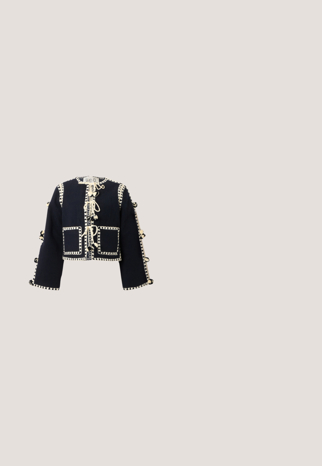 Chaqueta corta de manga larga negra con costuras decorativas en color crema, bolsillos frontales y lazos con pompones a lo largo del centro y las mangas.; Vestido maxi negro con finas tirantes ajustables, escote con volantes y detalles de botones en la cintura. Hecho de una tela ligera con una textura sutil.; Zapato negro de tacón bajo con tachuelas redondas doradas y un pequeño lazo negro en la punta, vista lateral sobre fondo blanco.; Gafas de sol ovaladas negras con montura metálica dorada y lentes oscuras degradadas, colocadas sobre una superficie blanca.; Bolso negro tejido con flecos en los bordes, cierre circular dorado y cadena dorada para el hombro.; Delicado collar de cadena dorada con pequeños filigranas florales y colgantes de flores incrustadas con cristales distribuidos uniformemente a lo largo de su longitud.