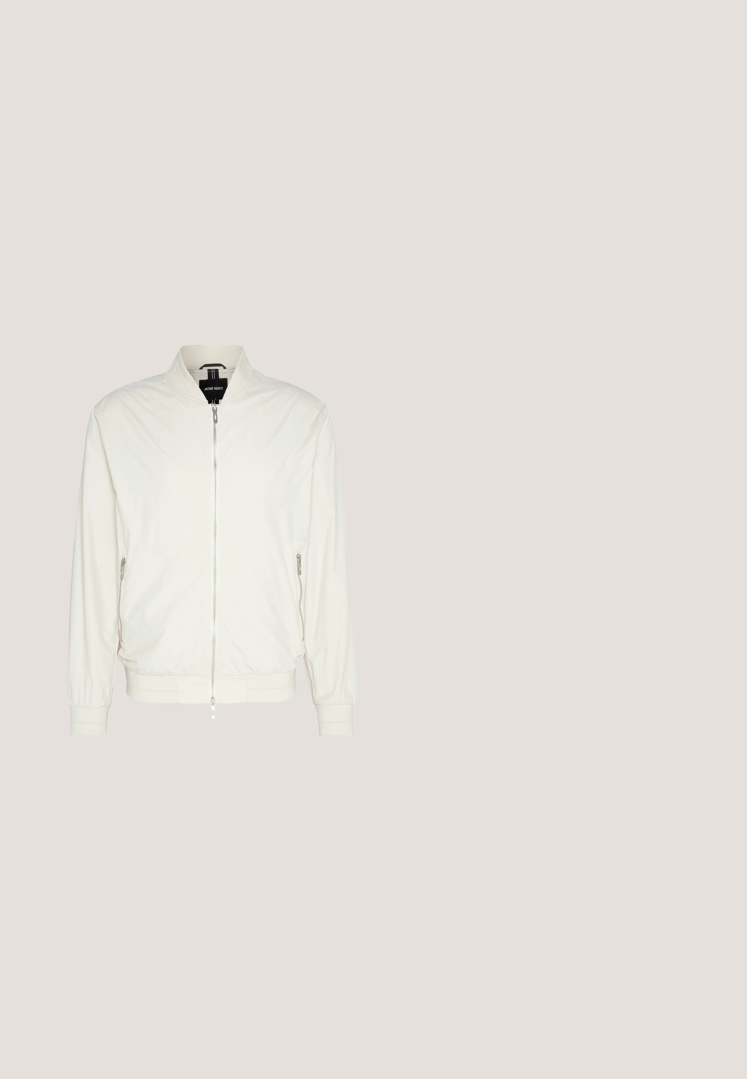 Veste bomber beige clair en tissu texturé, avec col montant, fermeture éclair à l'avant et poches zippées sur les côtés. Cuffs et ourlet côtelés.; Pull over gris avec un col haut et des manches longues. Fabriqué à partir d'un matériau lisse et doux, il possède une coupe ajustée et des accents côtelés au niveau de l'ourlet.; T-shirt en coton blanc à manches courtes, design col rond et texture lisse. Étiquette visible au niveau du col. Style simple et classique.; Pantalons ajustés de couleur beige clair fabriqués en tissu doux. Ils disposent d'une fermeture à bouton, de passants de ceinture et d'une coupe slim avec des jambes droites et une texture minimale.; Bottine Chelsea en cuir noir flottant au-dessus d'un banc en bois, avec de l'herbe et des plantes en arrière-plan.; Ceinture en cuir noir avec une boucle en métal argenté rectangulaire, au design plat et à la texture lisse. Les extrémités s'effilent pour un enfilage facile.