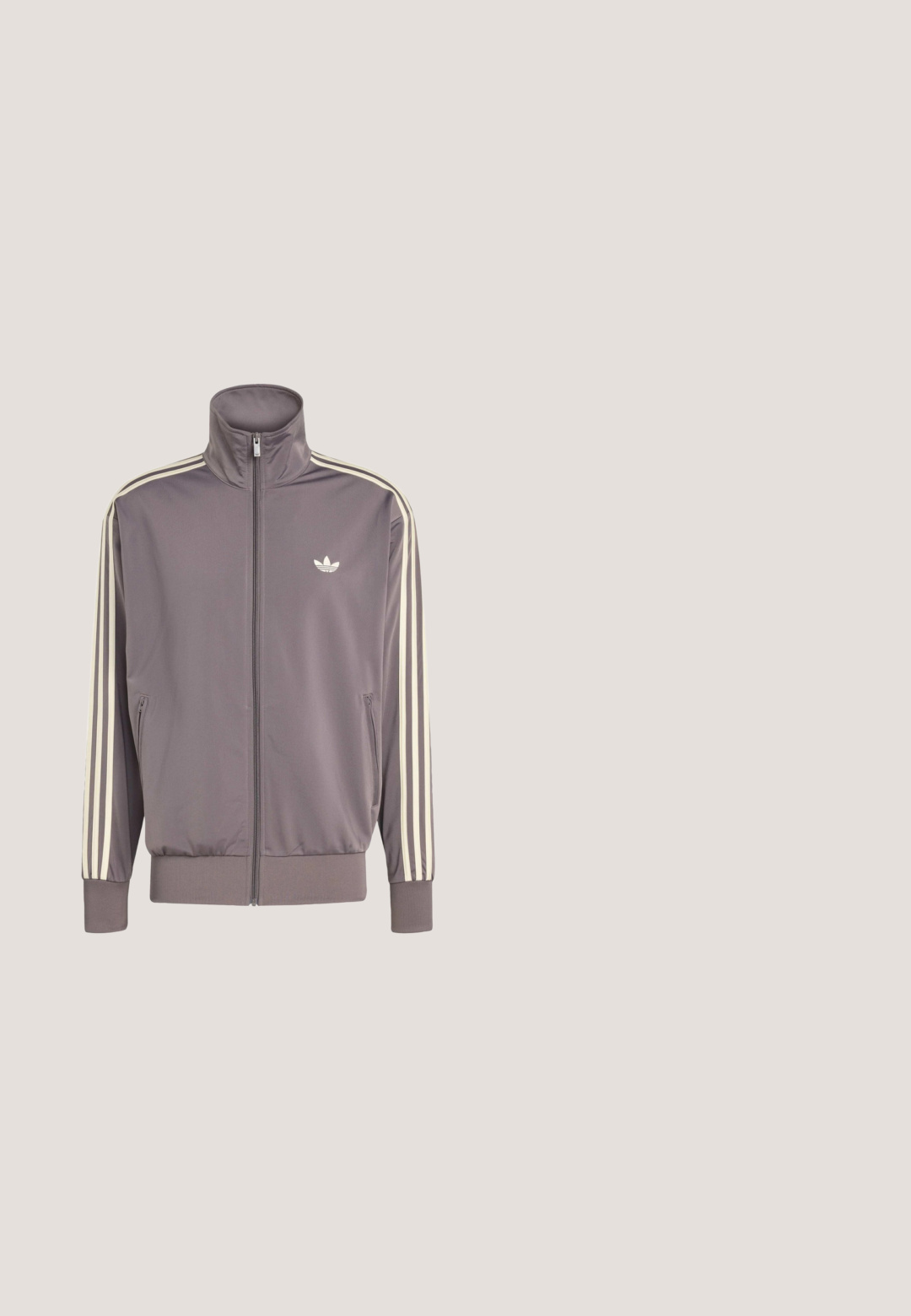 Grijze trainingsjack met hoge kraag, volledige ritssluiting en elastische manchetten. Bevat witte strepen op de mouwen en een klein logo op de borst.; Bruine Adidas T-shirt met gele bies aan kraag, mouwen en drie strepen langs de schouders en bovenarmen, met een klein trefoil-logo.; Zwarte sportbroeken met een comfortabele elastische band, twee zijvakken en een gladde, lichte stof. Met subtiele logo-details.; Zwarte waterdichte rubberlaars met een verstelbare gesp, een gestructureerd oppervlak, een licht gebogen vorm en een robuust profiel voor grip.; Zwarte sportzonnebril met grote groene lenzen, hoekig ontwerp en een matte afwerking. Heeft een opvallende neusstang en gestructureerde armen.; Zwarte cilindrische duffelbag met dubbele handvatten, verstelbare schouderriem, ritssluiting aan de zijkant en klein gouden lauwerkranslogo.