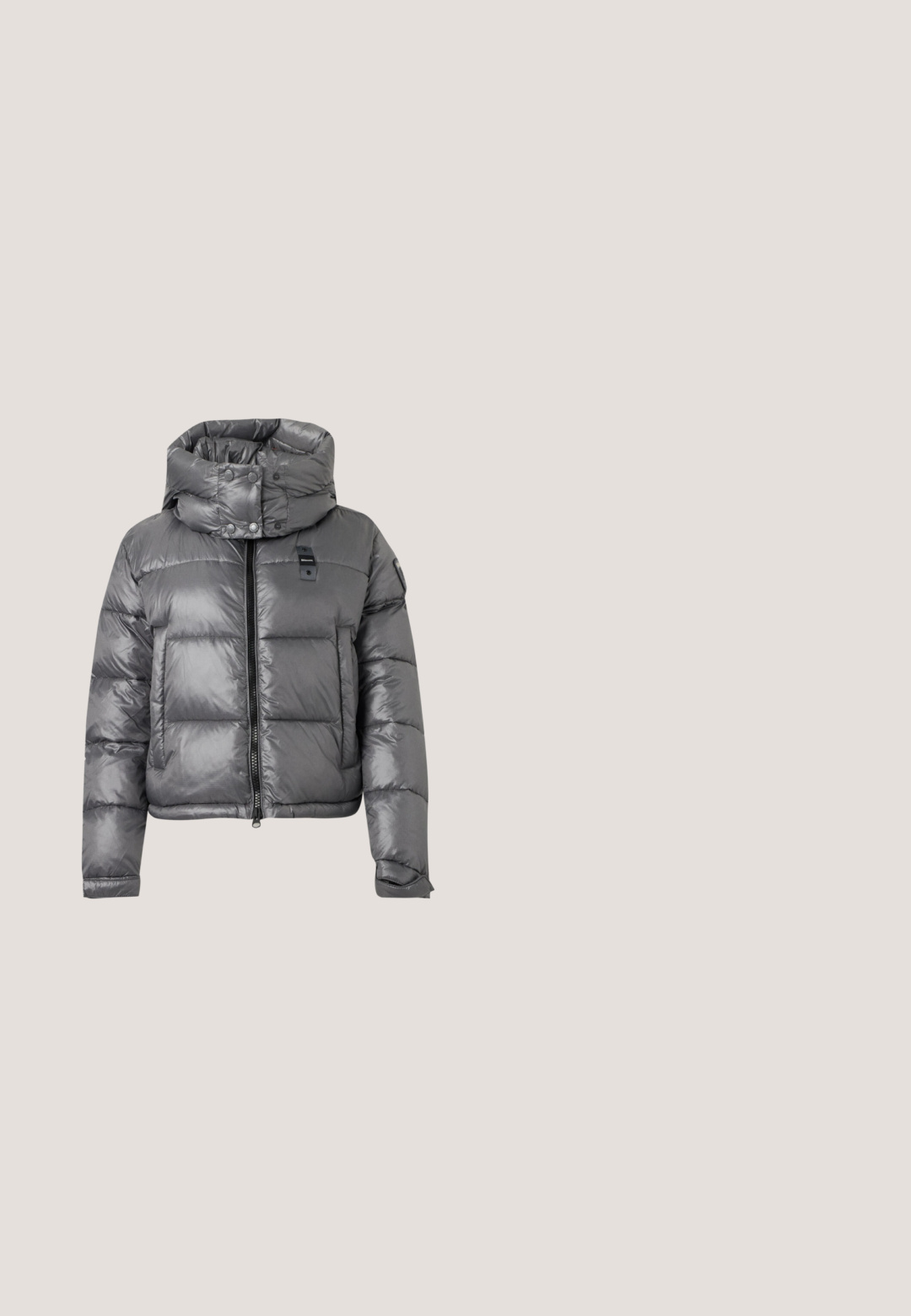 Grå skinnende puffjakke med høj krave, lynlås foran, trykknapper og lange ærmer med justerbare manchetter.; Marineblå V-hals langærmet sweater med ribbet kant og ærmeafslutninger, vist mod en lysegrå baggrund.; Blå denimjeans med vid ben og høj talje. Indeholder fem lommer, knap- og lynlåslukning foran samt diskret falming på stoffet.; Sort læder ankelstøvle med rundt tå, blokhæl, lynlås i siden og stikninger på vampsiden. Glat tekstur, klassisk design.; Sort textured læderhåndtaske med en rullet håndtag med en sølv metalstang og en justerbar skulderrem med spænde.; To sølvfarvede kompakte spejle formet som muslingeskaller med ribbede detaljer, placeret side om side på en hvid baggrund.