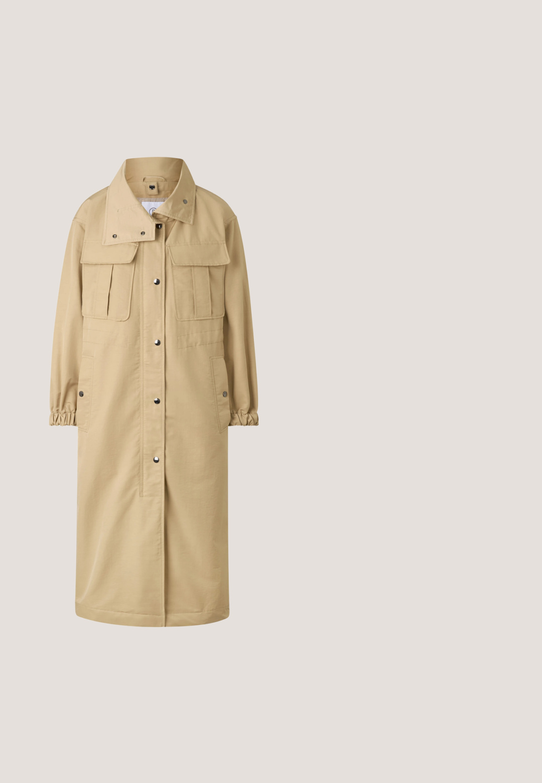 Lange beige jas met drukknoopsluiting aan de voorkant, twee borstklepzakken, zijzakken, elastische manchetten en een hoge kraag.; Beige v-hals trui met lange mouwen. Heeft een ontspannen pasvorm, geribbelde zoom en een zachte textuur. Eenvoudig ontwerp zonder patronen of accenten.; Witte linnen shirt met een knoopsluiting aan de voorkant, een spread collar en driekwart mouwen. Kenmerkt zich door een geweven stof en een subtiele glans.; Beige katoenen broek met een relaxed fit, voorzien van een gevlochten bruin leren riem en opgerolde uiteinden. Soepele textuur, standaard zakken.; Beige suède instapper met een ronde neus, gestikte details en een rubberen zool met kleine nopjes voor grip. Zijaanzicht.; Beige neplederen tote bag met twee handvatten, voorzien van het reliëf "JOOP! JEANS" logo en hexagonale hardware accenten. Gladde textuur en een open bovenkant.