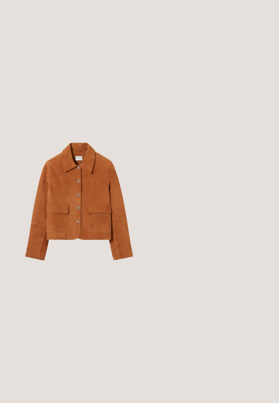 Chaqueta de ante marrón con cuello con solapa, cierre de botones a presión y dos bolsillos delanteros. Presenta un logo bordado en el dobladillo.; Camisa de manga corta con botones y un vibrante patrón de frutas y hojas en naranja, verde y azul verdoso sobre fondo oscuro.; Vaqueros acampanados de mezclilla azul claro con cintura alta, que cuentan con cinco bolsillos, costuras contrastantes y una textura suave.; Sandalia de tacón de ante marrón con una cinta ancha y detalles recortados, adornada con tachuelas de latón y un tacón de bloque de madera.; Gafas de sol redondas con montura de carey, lentes en degradado rosa y varillas delgadas con acentos dorados.; Cinturón de ante marrón enrollado con una gran hebilla ovalada de latón sobre un fondo claro.