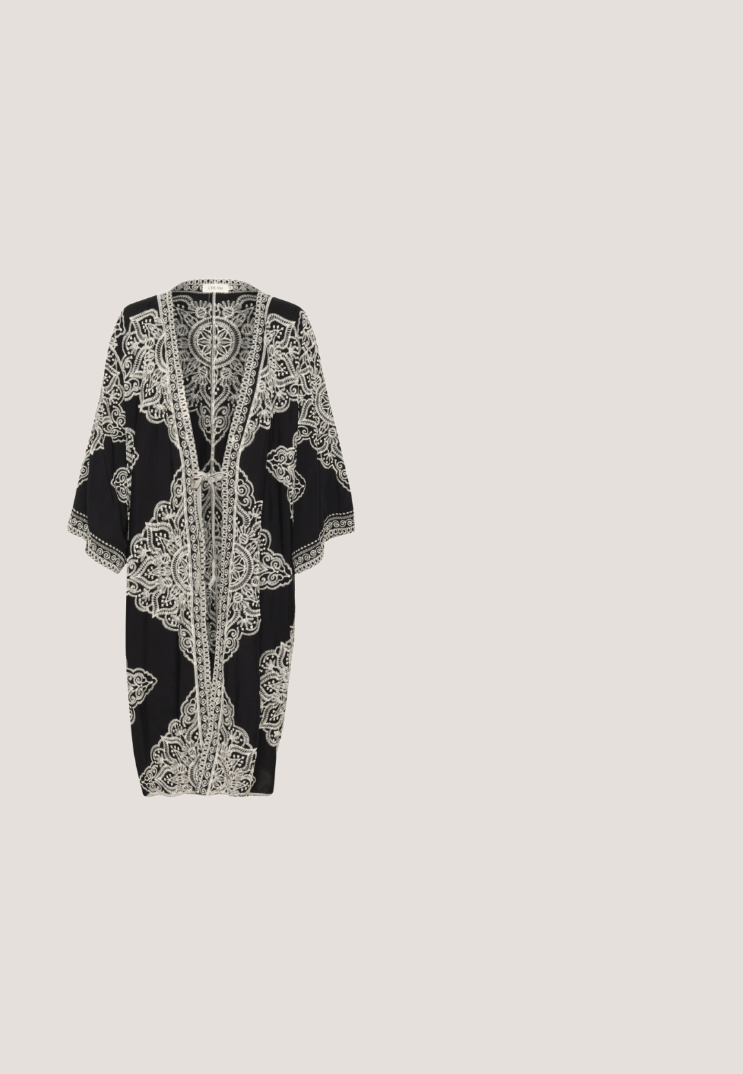 Cubierta estilo kimono negra con intrincados patrones de encaje blanco, mangas sueltas, abertura frontal y cierre con lazo. Tejido suave con un diseño fluido.; Mono sin mangas negro con escote en V, cierre de botones en el frente, cinturilla elástica y corte relajado, con una textura de tela suave y pantalones cortos.; Chancla negra con suela de goma, que presenta un diseño de sola tira con tres ranuras horizontales. Textura plana y suave sin patrones adicionales.; Gafas de sol en carey marrón con un marco audaz y angular. Las lentes degradadas pasan de oscuras a claras. Presentan un sutil logo en el costado.; Bolso tote tejido negro con asas trenzadas, ribete de lentejuelas plateadas cerca de la parte superior y una pequeña etiqueta metálica de la marca en el frente.; Pulsera de tono dorado con una cadena delicada y múltiples charms texturizados en forma de concha distribuidos uniformemente a lo largo de ella.