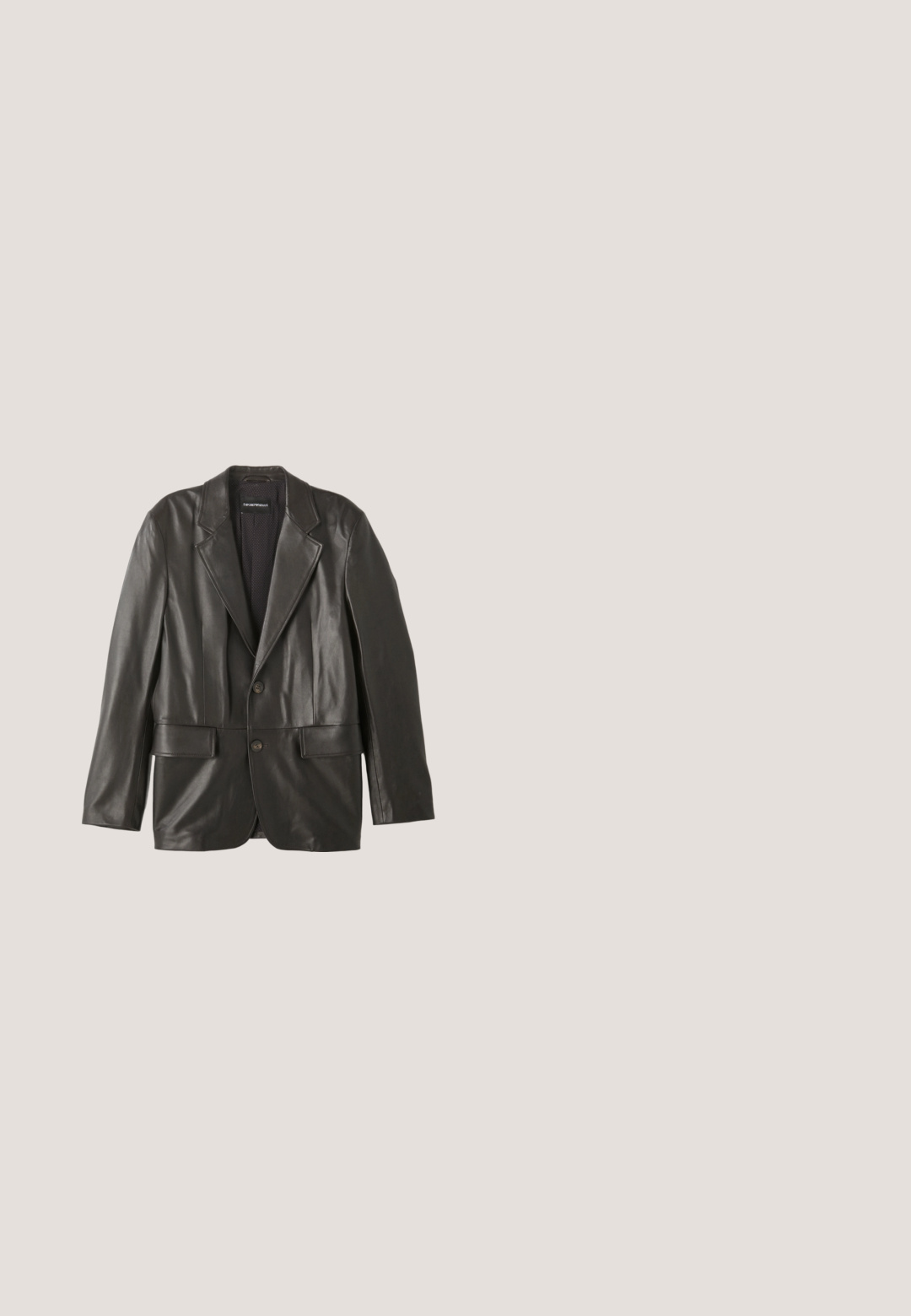 Sort læderblazer med klapkraver, to knapper og klaplommer, lagt fladt mod en hvid baggrund.; Hvid skjorte med knapper lavet af bomuld, med klassisk krave, lange ærmer og subtil broderi på venstre bryst. Har beige knapper.; Lysegrå skræddersyede bukser med bæltestropper og presserynke foran, fladt vist mod en hvid baggrund.; Sorte læder dress sko med rund tå, dekorative perforeringer langs kanterne og en flad hæl. Har et snørebåndsdesign.; Sort lædermappe med tekstureret frontpanel, dobbelte top-håndtag, aftagelig skulderrem og lille sølvlogo i nederste højre hjørne.; Sort læderbælte løst rullet med mat sort rektangulært spænde og flere justeringshuller på en hvid baggrund.