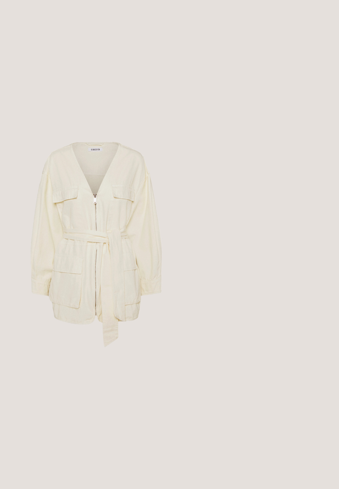 Crème katoenen jack met lange mouwen, een V-hals, een ritssluiting aan de voorkant, twee opgestikte zakken en een gestrikt tailleband. Soepele textuur, relaxte pasvorm.; Beige linnen mouwloze jumpsuit met wijde pijpen, brede schouderbanden en twee grote voorzakken, getoond op een effen witte achtergrond.; Beige slippersandalen met een brede teband en een dikke, ronde zool. Beschikt over een glad bovenmateriaal en een contrasterend bruine voetbed.;  schildpad zonnebril met een hexagonale montuur, bruine lenzen en een gouden 'QUAY' logo op de arm. Gladde textuur, stevige constructie.; Geweven rieten handtas in lichtbeige met een franjerand, gouden hardware en een ronde sluiting; voorzien van een kettingriem.; Gouden ketting met gelijkmatig verdeelde kleine groene stenen kralen op een lichte, neutrale achtergrond.