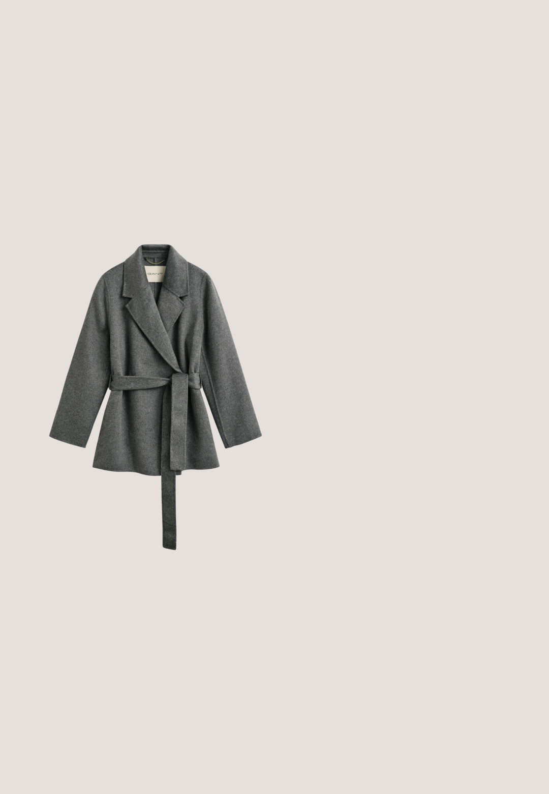 Manteau portefeuille ceinturé en mélange de laine gris foncé avec larges revers et manches longues, suspendu avec étiquette GANT visible à l'intérieur du col.; Pull en tricot gris, col rond, manches longues, fabriqué en un mélange de laine douce, avec des poignets et un ourlet côtelés, présentant une finition de texture moyenne.; Pantalon en laine grise avec une texture subtile, présentant une coupe droite, des poches latérales et un ourlet à revers. Détail de ceinture noire.; Bottines Chelsea en cuir noir avec des panneaux latéraux élastiques, bout arrondi et un petit talon en bloc. Texture lisse et design minimaliste.; Sac de voyage en cuir noir avec une finition texturée, deux poignées supérieures, une bandoulière amovible et des accents de quincaillerie argentée.; Boucles d'oreilles pendantes en argent en forme de double cœur avec deux cœurs brillants reliés sur chaque boucle, sur fond blanc.