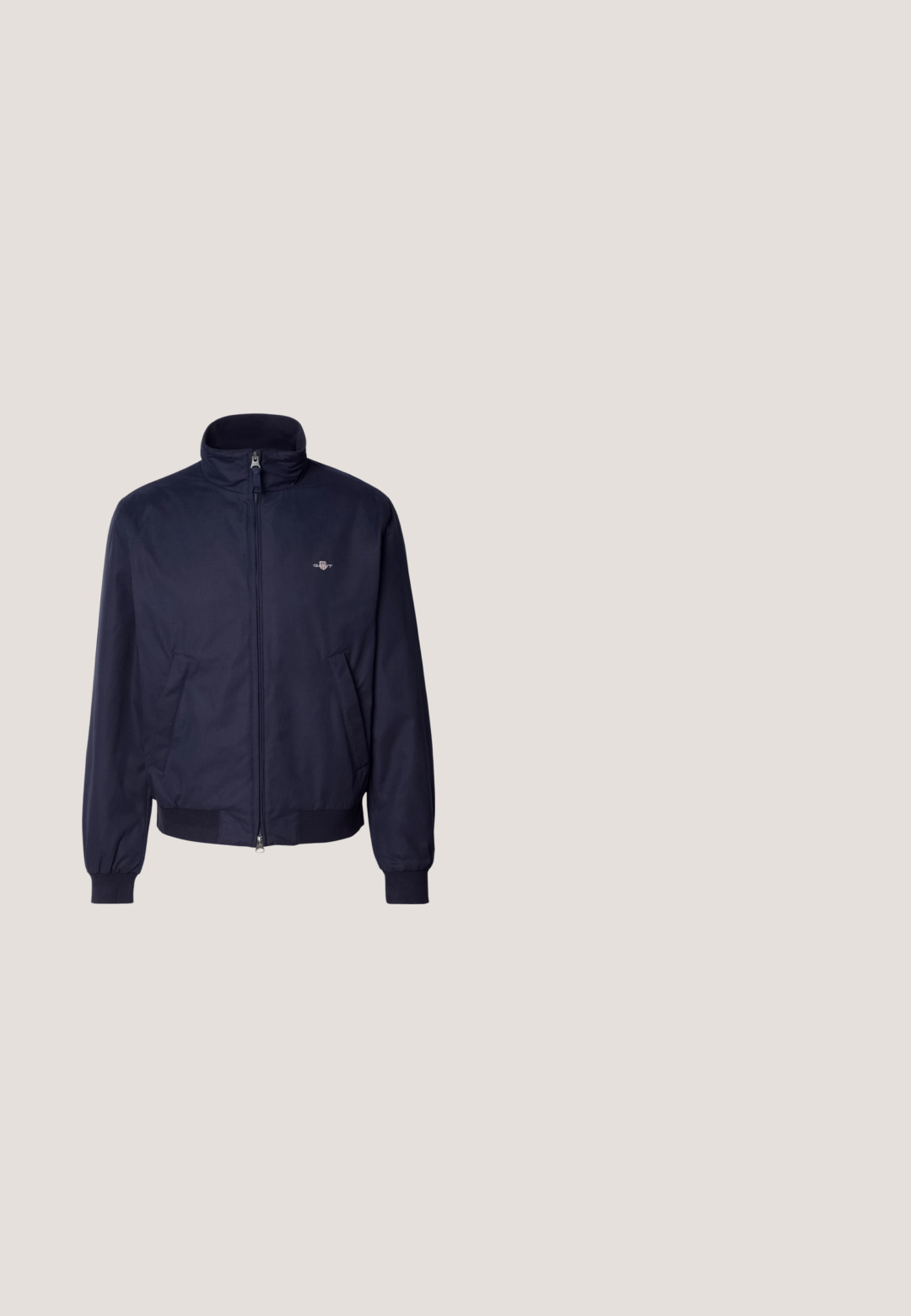 Marineblauwe bomberjack van gladde stof, met een opstaande kraag, voorrits, elastische manchetten en zijzakken. Subtiele logodetail aanwezig.; Marineblauwe pullovertrui met een halve ritssluiting, zachte gebreide textuur, lange mouwen en een klein logo op de linkerborst.; Navy blauwe katoenen t-shirt met korte mouwen, een ronde hals en witte bedrukte tekst: "GANT 32 EAST 39TH ST. NEW YORK" op de borst.; Blauwe rechte spijkerbroek met vijf zakken en een knoopsluiting aan de voorkant op een witte achtergrond.; Bruine suède enkelboot met zwarte veterogen en veters, ronde neus en een zwarte rubberen zool. Toon een gestructureerd oppervlak en een hiellus.; Tote bag van wit canvas met marineblauwe accenten. Voorzien van twee stevige handvaten en een logo patch op de voorkant. Rechthoekige vorm.