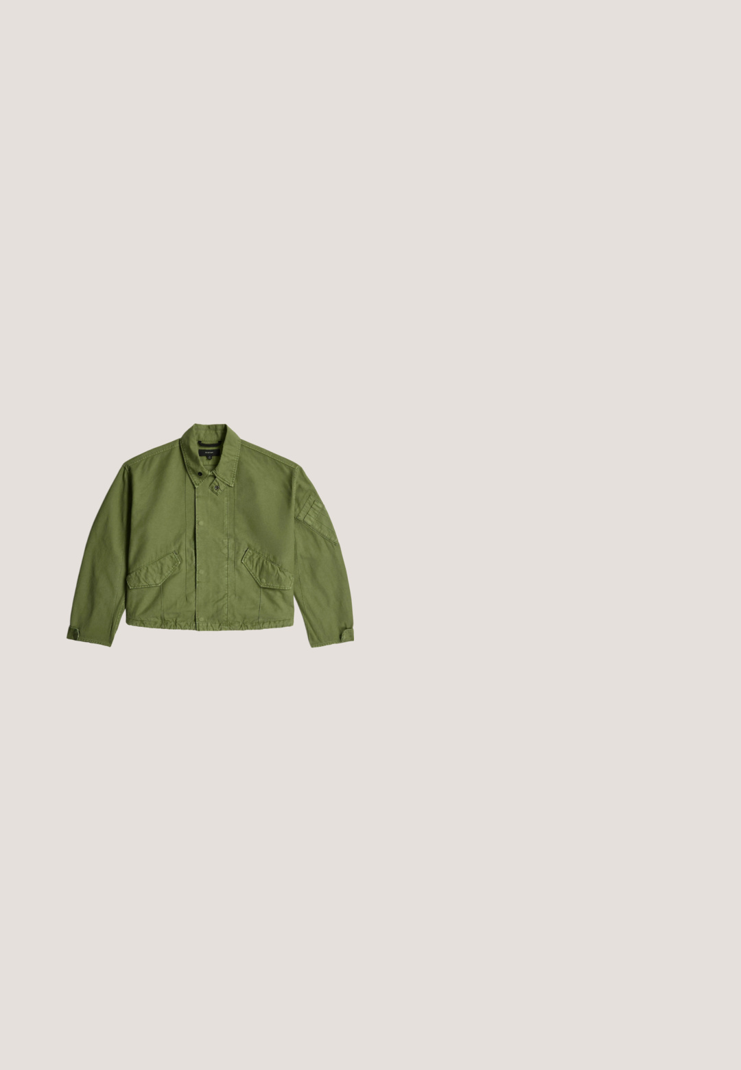 Olijfgroene cropped jas met knoopkraag, klepzakken aan de voorkant, verstelbare polsbandjes en subtiele naaddetails op de mouwen.; Olijfgroene katoenen T-shirt met een hoge, ronde halslijn, korte mouwen en een losse pasvorm. Gladde textuur, geen zichtbare patronen of accenten.; Olijfgroene cargobroek met meerdere zakken, een taille met trekkoord en een relaxte pasvorm. De stof heeft een zachte textuur en een stevige, duurzame uitstraling.; Lage Puma sneaker in roomkleur met donkerbruine accenten, veters en gespikkeld patroon op de zijstreep.; Donkergroene versleten leren crossbodytas met zwarte bies, lange verstelbare band en zichtbare voorvak met ritssluiting.; Gouden stervormige hangerketting met een langwerpig ontwerp en puntige uiteinden, opgehangen aan een fijne gouden ketting. Gepolijste afwerking.