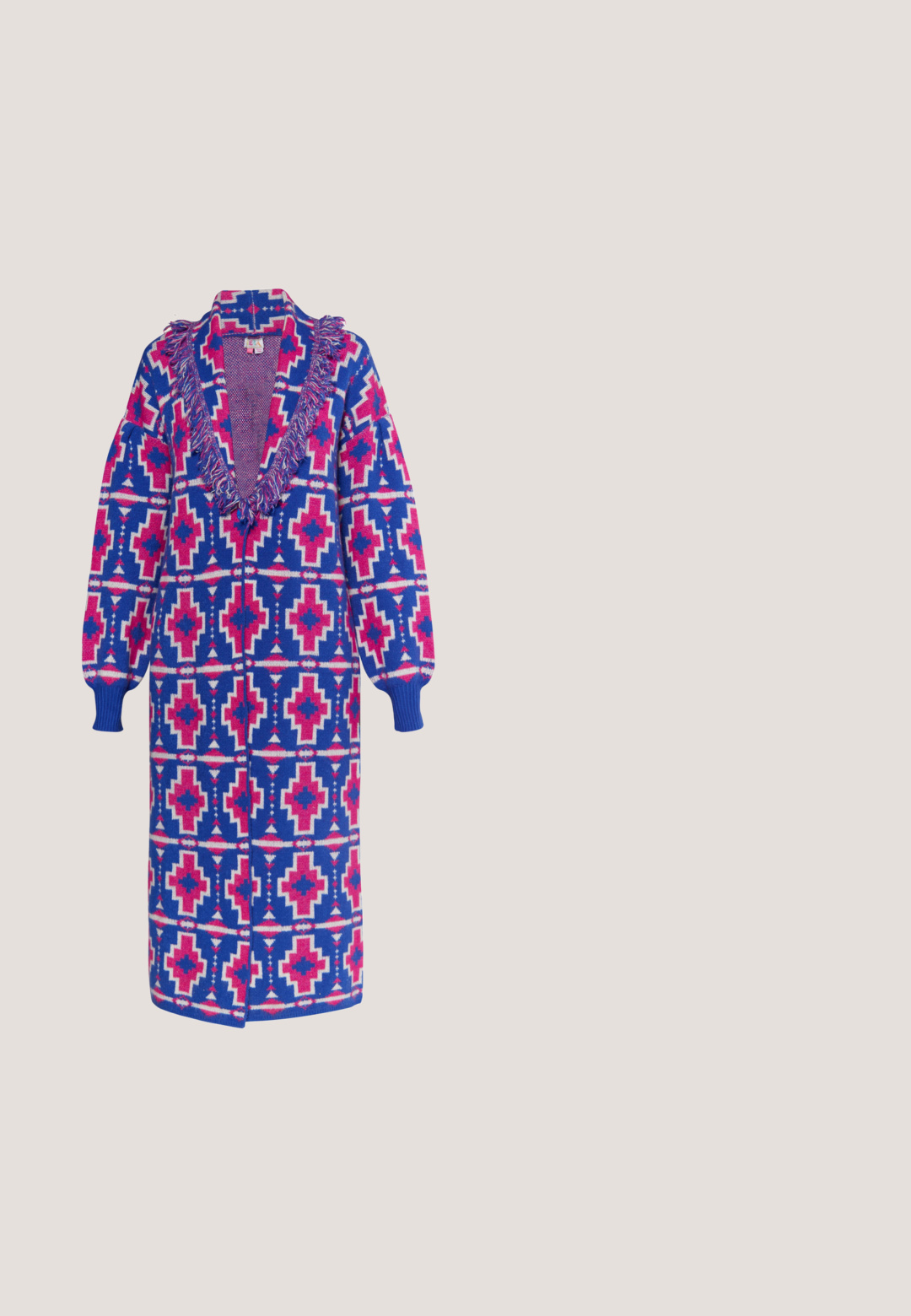 Lange gebreide buitencoat in blauw, roze en wit met geometrische patronen, een franjerand bij de halslijn en geribde mouwen. Open voorzijde ontwerp.; Trui met lange mouwen en kabelgebreid patroon met abstracte gebogen strepen in blauw, zwart, lichtblauw en crèmekleuren.; Paarse broek met wijde pijpen en open gehaakte structuur, hoge taille en een rechte brede silhouet.; Westerse enkellaars in zwart, metallic paars en huidskleur. Kenmerken zijn de spitse neus, blokhak, decoratieve uitsparingen en verticale geribbelde accenten.; Franje handtas van bruin leer, versierd met meerkleurige synthetische stroken. Heeft een gebogen bovenkant en een enkele verstelbare schouderband.; Twee kleurrijke bloemige oorbellen met doorschijnende bloemblaadjes, de ene in beige en groen, de andere in blauw en bruin, elk afgewerkt met een stekelige kraal.