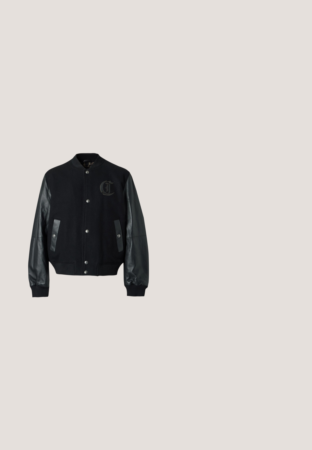 Veste varsity noire avec manches en cuir, boutons-pression sur le devant, deux poches latérales, poignets et ourlet côtelés, et une lettre noire brodée sur la poitrine.; Polo noir à manches courtes avec trois boutons et un logo vertical déformé "EMPORIO ARMANI" sur le côté gauche de la poitrine.; Jeans noirs à jambes droites avec cinq poches et des détails délicatement usés sur un fond clair uni.; Bottes en cuir noir à lacets avec une tige haute, bout rond, semelle en caoutchouc robuste et détail de logo sur le côté. Œillets en métal ajustables.; Lunettes de soleil noires avec une monture rectangulaire et des verres gris dégradés. Dotées d'une finition mate et de branches fines avec un détail de marque subtil.; Trousse de toilette rectangulaire noire avec poche avant zippée, poignée latérale et étiquette de marque rectangulaire argentée sur fond uni clair.