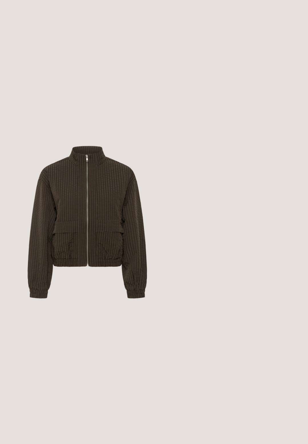 Dunkelbraune Reißverschlussjacke mit kleinem weißem Karomuster, hohem Kragen, zwei großen Frontklappentaschen sowie elastischen Bündchen und Saum.; Schwarzes T-Shirt mit kurzen Ärmeln, drei Cartoon-Hunden und dem Text "Low Riders Do It Better" in Hellbeige.; Weit geschnittene Hosen mit hoher Taille in Olivgrün mit Knopf- und Reißverschluss, Gürtelschlaufen und ausgefransten Säumen.; Flacher dunkelbrauner Sneaker mit strukturiertem Obermaterial, Schnürung vorne und hellbrauner Gummisohle mit Aufschrift Natural Soft.; Schwarze Lederschultertasche mit vorderer Reißverschlusstasche, gesteppten Details, verstellbarem Riemen und breitem Tragegriff vor weißem Hintergrund.; Silberne Kettenhalskette mit einem gedrehten Design, kreisförmigem Toggle-Verschluss und glatter, polierter Oberfläche.