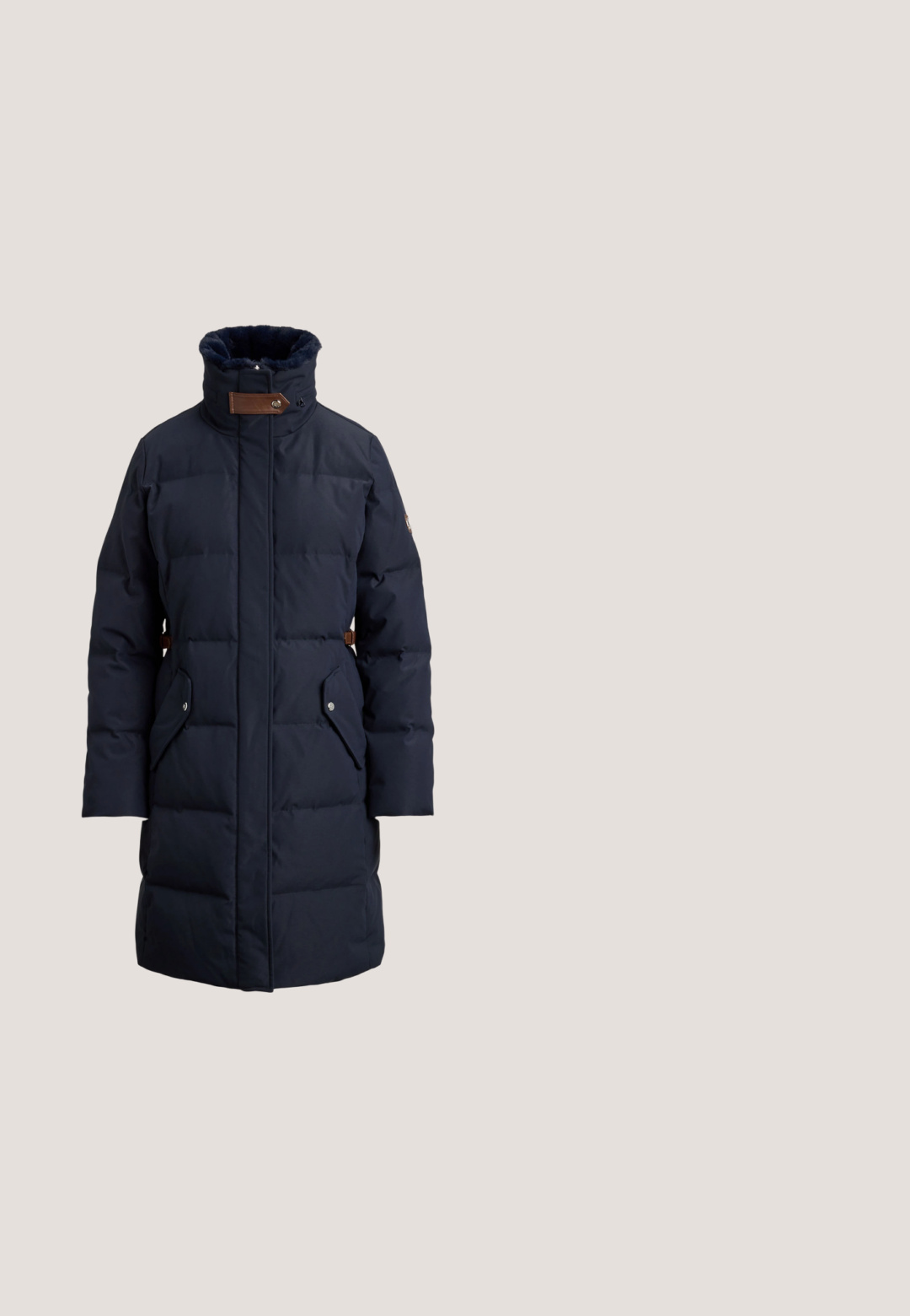 Mørkeblå pufferjakke med høj krave, horisontalt quiltet design, to sidelommer og brune læderdetaljer ved halsen.; Denimskjorte i mørkeblå, med krave, knaplukning fortil og to brystlommer med klapper. Lange ærmer med knapmanchetter.; Lang, plisseret nederdel i mørkegrøn med en bred talje, der har brandnavnet "LACOSTE" i kontrasterende grøn skrift.; Brune læder loafers med et tekstureret brunt stofpanel og guldfarvet hardware detaljer. Smal profil og syet pynt på siderne.; Olivengrøn Michael Kors-håndtaske med guldkæde skulderrem, buet top og lille gyldent logo foran, vist mod hvid baggrund.; Gul blomstformet broche med fem buede kronblade, der har en glat finish og en rund centrum, der fremhæver glatte, reflekterende overflader.