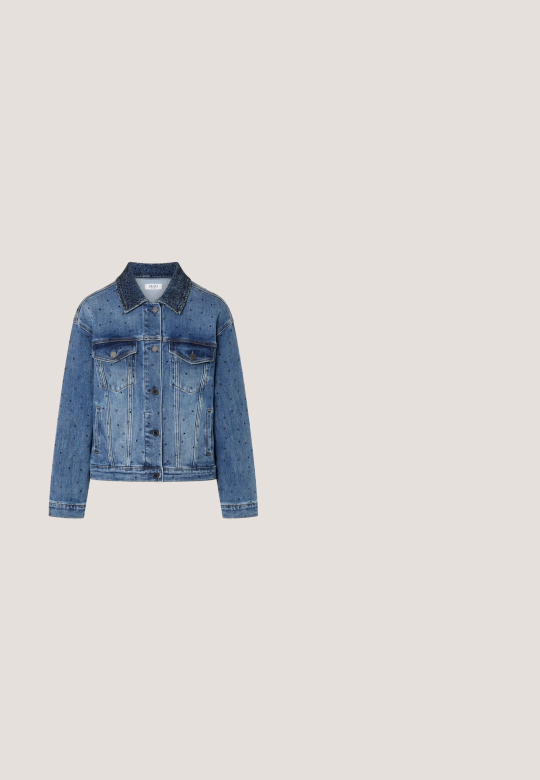 Blauwe spijkerjas met overal zwarte strassversieringen en een donkere, zwaar met kraaltjes bewerkte kraag. Twee borstzakken met knopen.; Blauwe denim overhemd met lange mouwen, drukknoopsluiting, puntige kraag en strass-details langs de schouderpas en kraagranden.; Zilver metallic wijde jeans met een hogere taille, voorzien van zakken en een vlinderprint detail op de linkerdij. Textuur met glanzende afwerking.; Lichtblauwe denim enkellaars met een spitse neus, gestructureerd oppervlak, decoratieve uitsparingen en zilveren studs. Heeft een zwarte wiggenhiel.; Denim schoudertas met gevlochten riem, gestikte spiraalvorm met studs, dubbele riemaccenten en decoratieve kwastjes en hangers op een witte achtergrond.; Twee zilveren manchetarmbanden in de vorm van riemriemen met gedetailleerde gespen en decoratieve patronen op een witte achtergrond.
