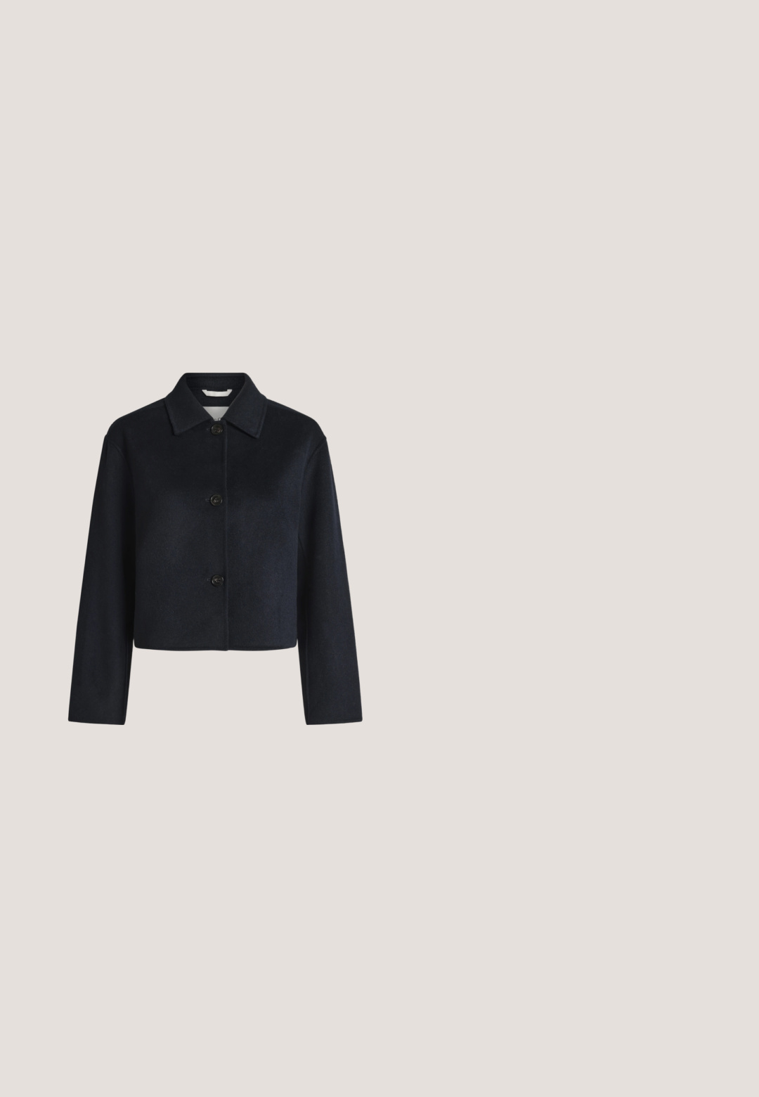 Veste noire courte avec manches longues, trois boutons à l'avant et un col pointu sur un fond clair uni.; Haut sans manches blanc avec un col montant, en tissu doux, présentant des détails froncés au niveau du col et une fermeture éclair dissimulée à l'arrière.; Pantalons bleu marine avec un lien à la taille, poches latérales et une coupe ample. Fabriqués dans un tissu lisse avec un subtil éclat. Design ajusté avec des plis.; Mocassin en cuir noir flottant au-dessus d'un tapis bleu texturé avec un canapé gris flou en arrière-plan.; Sac cabas en cuir noir avec double poignée et accents métalliques dorés, présenté sur fond gris clair.; Collier doré avec trois pendentifs irréguliers en forme de galets lisses sur une chaîne fine avec fermoir réglable.