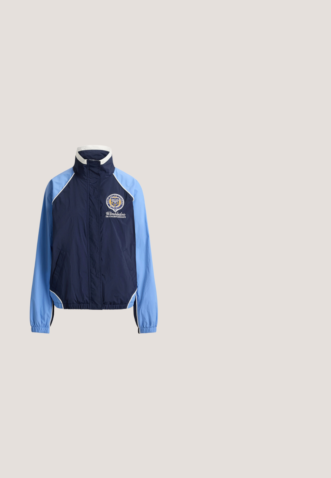 Chaqueta con cremallera azul marino y azul claro con ribete blanco, puños elásticos y logo de Wimbledon Championships en el pecho izquierdo.; Camiseta azul de manga corta con texto blanco "Lauren Ralph Lauren EST. 1996 NEW YORK" y logo de escudo en el frente.; Pantalones cortos azul marino con cintura elástica blanca y cordón, pequeño logo bordado en el dobladillo izquierdo, emblema del Campeonato de Wimbledon en la pierna derecha.; Zapatillas blancas con upper de cuero liso, punta redonda, suela plana y detalles sutiles en los paneles laterales. Diseño con cordones y un interior suave.; Bolso de lona azul marino con dos asas superiores y correa ajustable, con bandas de acento en gris. La tela parece duradera y estructurada.; Pendientes de aro de oro con piedras preciosas azules rectangulares colgando en un engaste tipo bisel sobre un fondo blanco liso.