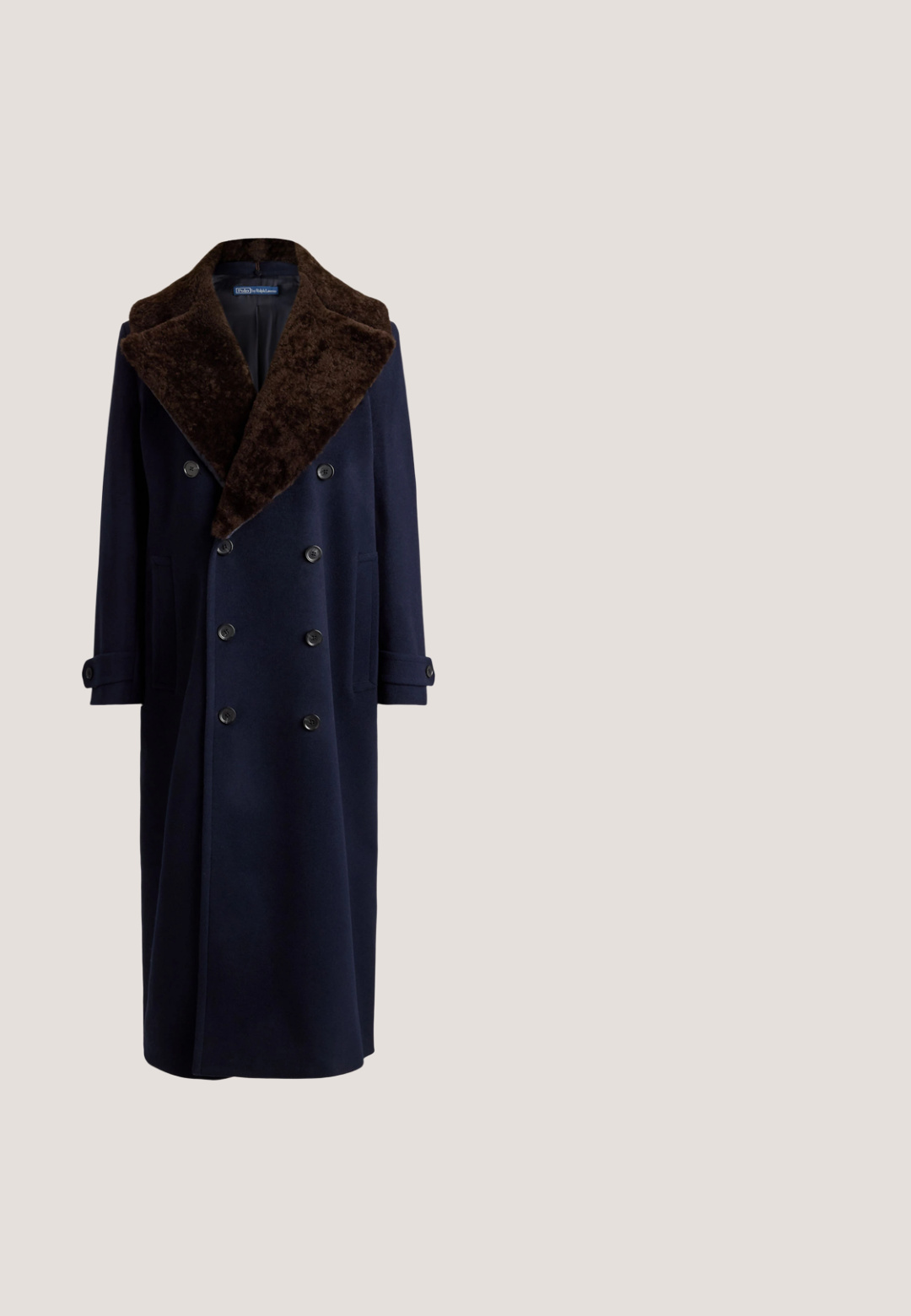 Langer dunkel marineblauer zweireihiger Mantel mit großem braunem Pelzkragen und geknöpften Manschetten auf einfarbig hellem Hintergrund.; Schwarzes Maxikleid mit Neckholder-Ausschnitt, das mit einem gebundenen Rücken, einer fließenden Form und einer strukturierten Oberfläche mit subtilen Details versehen ist.; Schwarze Wildleder-Pumps mit hohem Absatz und spitzem Zehenbereich, dekorativem Schleifenverschluss und schlankem 5 cm Absatz. Glatte Textur und klassische Silhouette.; Schwarze Cateye-Sonnenbrille mit dunklen Gläsern, goldenen Logoakzenten an der Vorderseite und den Bügeln, auf einer weißen Oberfläche präsentiert.; Schwarze Wildleder-Handtasche in halbmondförmigem Design mit einem Trageriemen und einem goldenen rechteckigen Verschluss mit einem kleinen eingeprägten Logo in der Mitte.; Goldarmband mit einem rechteckigen, gemusterten braunen Stein in der Mitte, der ein Logo trägt, und ergänzt durch kleine klare Edelsteine.