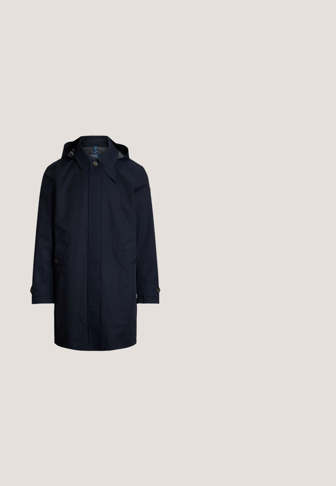 Abrigo impermeable azul marino con capucha, cierre de botones, dos bolsillos frontales y detalles en las mangas. Acabado exterior suave.; Sudadera con capucha azul marino con bolsillo delantero, capucha con cordón, texto rojo "POLO" y logo circular de Polo Ralph Lauren New York en el pecho.; Camisa de manga larga azul y blanca con rayas verticales, botones, cuello y pequeño logo bordado en el pecho izquierdo.; Pantalones deportivos beige con cordón, bolsillos laterales y logo y emblema rojo "POLO" en la parte superior del muslo izquierdo.; Zapatilla blanca con parte superior de cuero liso y textil, con detalles en azul y rojo, suela negra y un pequeño logo en el lateral.; Cinturón de tela negra entrelazada con hebilla rectangular plateada y punta de cuero negra, enrollado sobre un fondo blanco.