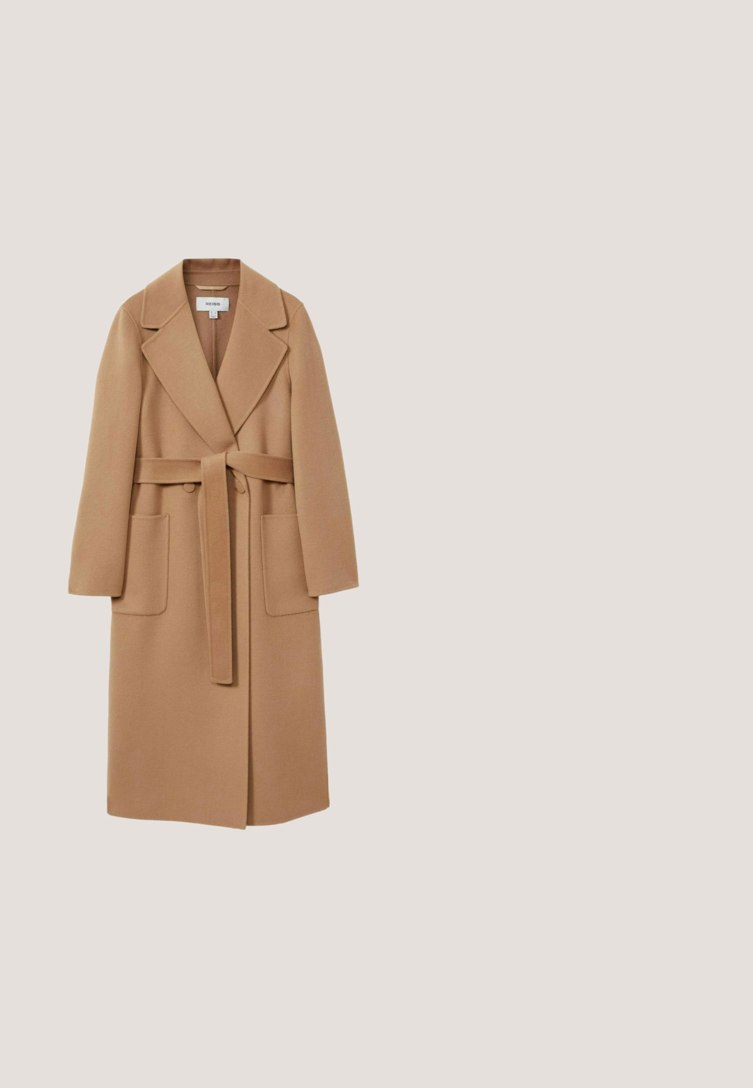 Lang, kamelfarvet frakke i blødt stof med bælte i taljen, brede reverser og to frontlommer. Glat tekstur og skræddersyet design.; Cremefarvet strikket sweater med lange ærmer og ribbede manchetter, krave og kant, som er lidt længere bagtil.; Beige højtaljede bukser med en afslappet pasform, der har pletter og en snøre i taljen. Materialet ser ud til at være tekstureret og let.; Lysebrun ruskindsløs loafer med en lav sort hæl og en bred remdetalje tværs over toppen, vist i sideprofil på hvid baggrund.; Foldet firkantet beige strikket uld tørklæde på hvid baggrund, der viser tekstur og blødt materiale.; Kremfarvet læder tote taske med præget blomster- og bogstavmønster, to skulderstropper og en lille metalplade med logoet JOOP! foran.