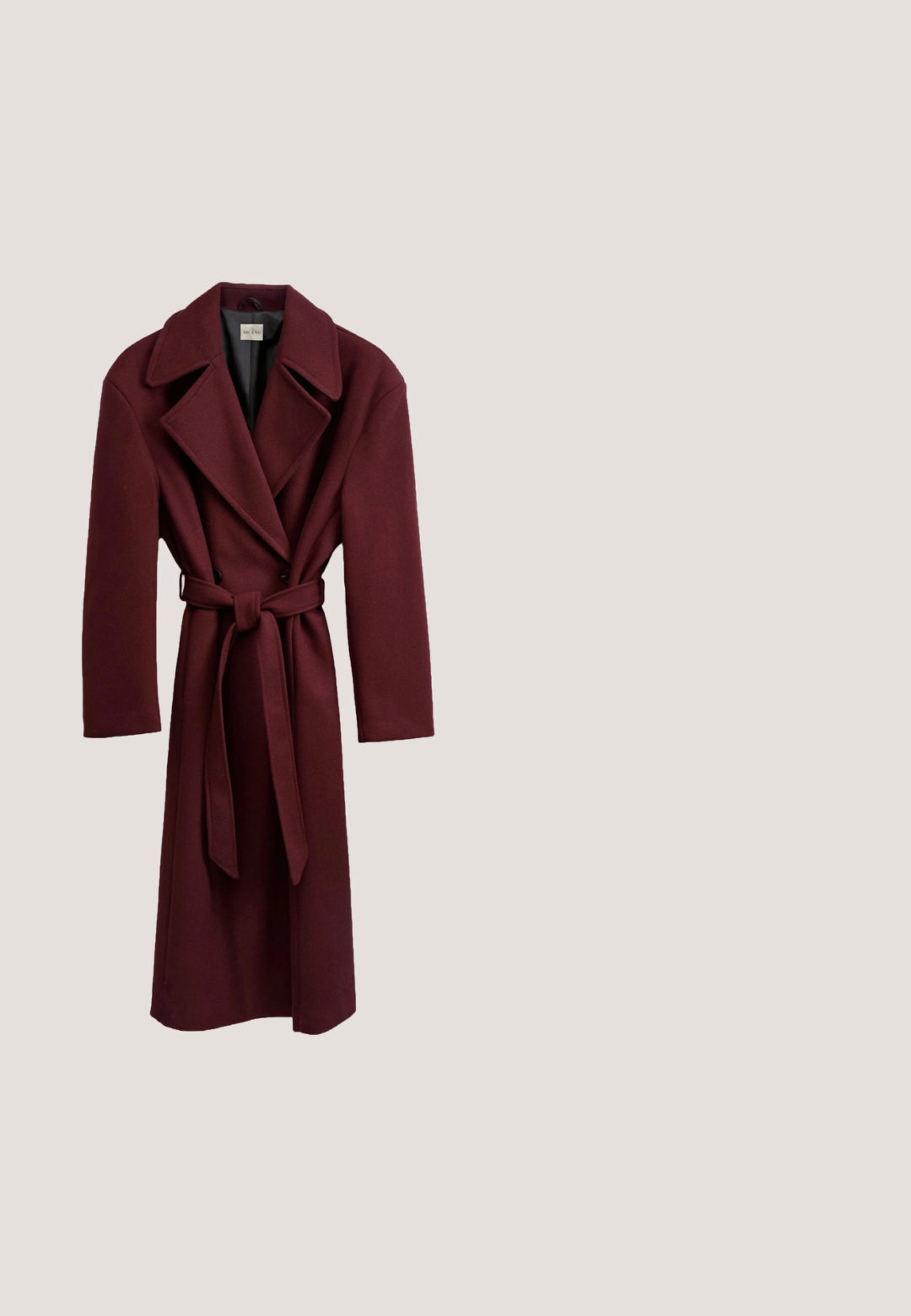 Bordeaux wollen jas met een lange silhouet, brede opstaande kraag, dubbele knoopsluiting aan de voorkant en bijpassende strikriem in de taille.; Bordeaux satijnen blouse met lange mouwen en een wikkelontwerp, geplooide details aan de zijkant en gestructureerde schouders. Gladde textuur, elegante silhoutte.; Bordeaux gebreide midi-rok met een aansluitende silhouette, gladde textuur en een tailleband. Geen zichtbare naden of patronen. Effen kleur door het hele stuk.; Bordeauxrode lakleren slingback met puntige neus, dunne enkelband en kleine decoratieve gespsluiting. Gladde textuur en hoge hak.; Donkerbruine suède handtas met donkerleren handvatten, voorflap met gouden knoop en afneembare schouderriem op lichte achtergrond.; Gouden ketting met rechthoekige rode edelstenen, gelijkmatig verdeeld over de lengte, met een sluiting aan één uiteinde.