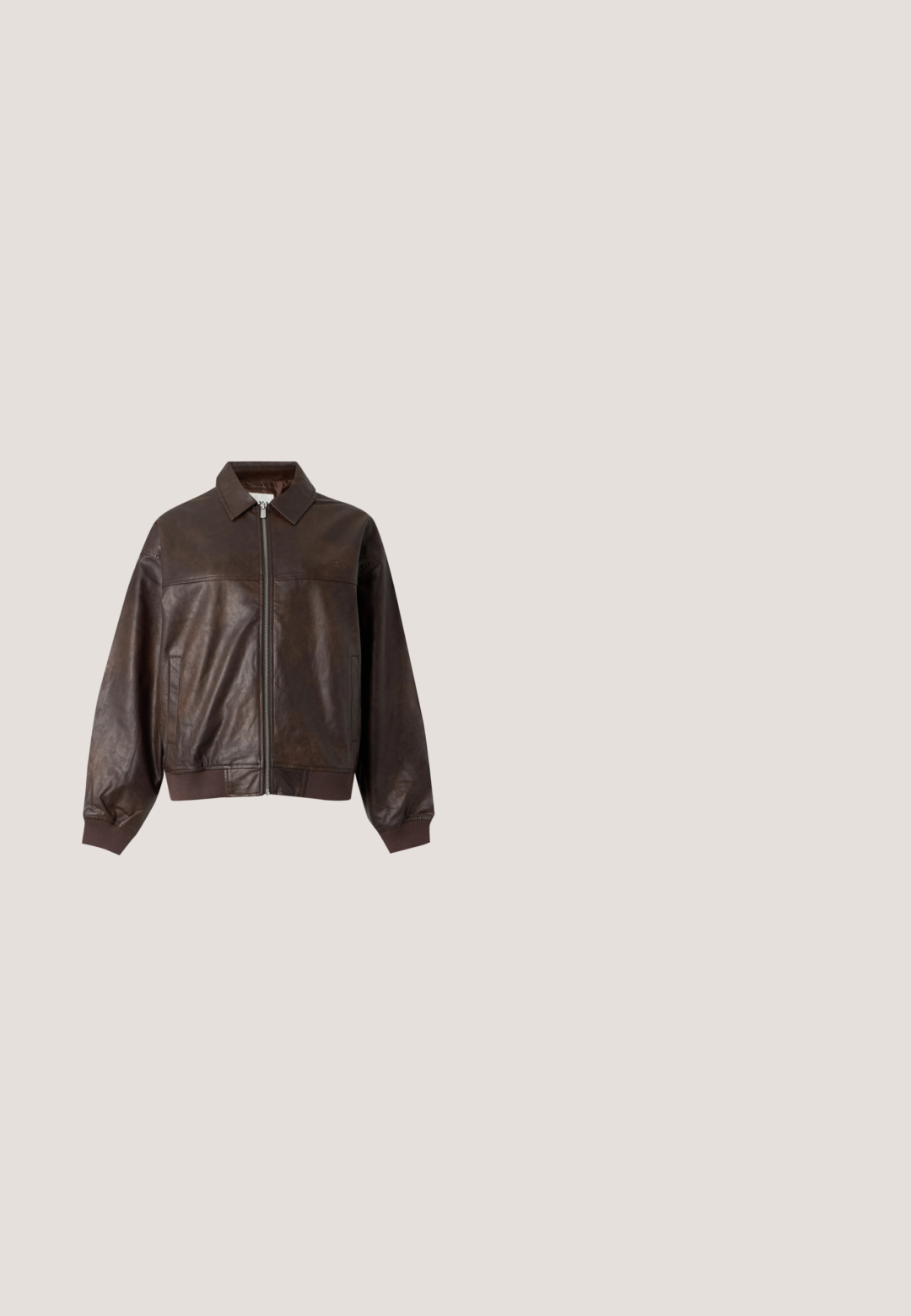 Veste en cuir marron foncé avec fermeture éclair à l'avant, col, poches latérales et poignets et bas côtelés, posée à plat sur un fond clair.; Vêtement gris sans manches avec plusieurs fermetures éclair délimitant un tissu drapé et une fermeture éclair centrale au dos.; Pantalon évasé en denim marron avec une finition délavée et texturée. Il dispose de cinq poches, passants de ceinture et d'une fermeture par bouton. Coutures plates et jambes larges.; Baskets compensées en daim fauve avec trois sangles Velcro, bout perforé, talon clouté et une étiquette suspendue portant l'inscription "BRONX" sur fond blanc.; Lunettes de soleil teintées marron avec une monture en écaille de tortue. Présentent une forme en œil de chat angulaire et des accents jaunes embellis sur les branches.; Petit sac bandoulière en suède marron foncé en forme d'ours, avec des accents noirs sur les pattes et les oreilles, et une bandoulière ajustable.