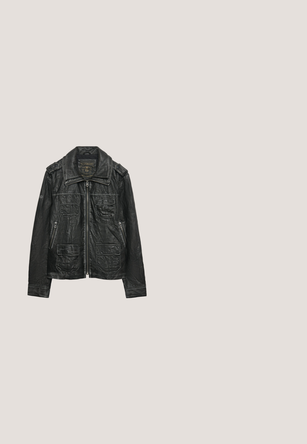 Chaqueta de cuero negro con cremallera frontal, cuatro bolsillos con solapa, bolsillos laterales con cremallera, hombreras y cuello ancho.; Jersey gris de lana tejido con mangas largas y cremallera corta en el cuello alto y redondo, con un patrón acanalado texturizado en toda la prenda.; Camisa de manga larga gris de tejido suave con cuello redondo y corte relajado, que presenta dobladillos cosidos y sin patrones ni acentos visibles.; Vaqueros de mezclilla gris oscuro con un diseño clásico de pierna recta, que incluyen bolsillos frontales, cremallera con cierre de botón y un ligero desgastado.; Botines negros hasta el tobillo con exterior de cuero liso, cierre frontal con cordones y cuello tejido gris. Presentan una suela de goma texturizada y detalles cosidos.; Bolsa de viaje de cuero negra con dos asas superiores, un compartimento principal con cremallera y un bolsillo frontal. Presenta detalles de metal en plateado y un parche con el logo.
