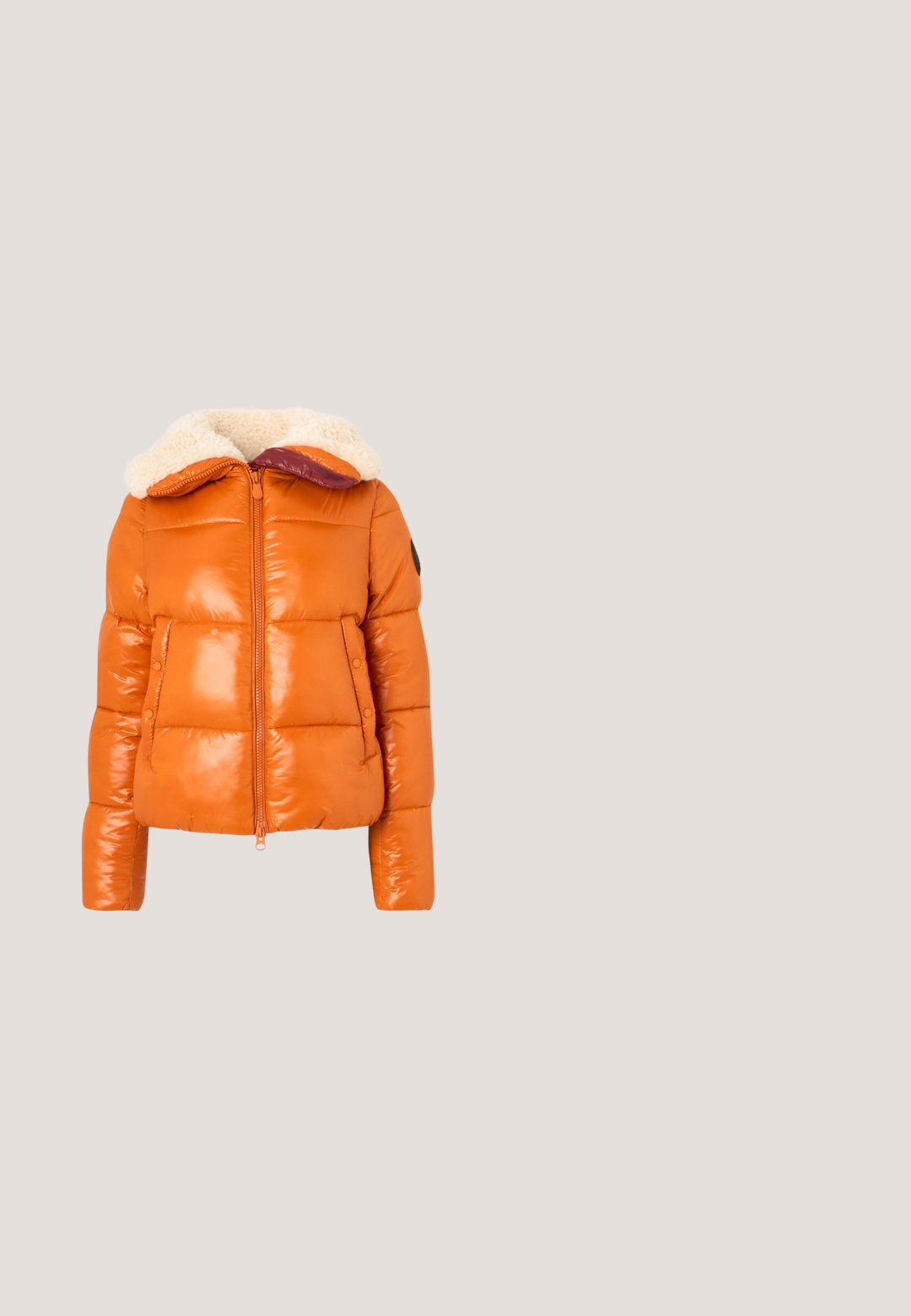 Puffjacke aus glänzendem orangefarbenem Material, mit einem sherpa-gefütterten Kapuzen, Reißverschluss vorne und geknöpften Seitentaschen. Boxy-Design mit gesteppten Abschnitten.; Patchwork-Pullover mit gelben, braunen, rosa und cremefarbenen Quadraten, vorne und an den Ärmeln mit lächelnden Gesichtern und Bärenmotiven.; Leuchtend orangefarbenes T-Shirt mit kurzen Ärmeln und Rundhalsausschnitt, schlichtes Design, auf hellem grauem Hintergrund dargestellt.; Hellbeige maßgeschneiderte Hose mit geradem Bein, Gürtelschlaufen und einem Frontreißverschluss.; Beige Wildleder-Sneaker mit einem herzförmigen Strassdesign, cremefarbener gepolsterter Kragen und Gummisohle. Schnürsenkel über die Vorderseite.; Braune Leder-Umhängetasche mit doppeltem goldfarbenen Reißverschluss und MCM-Logo-Muster, verstellbarem Riemen und Quasten an den Reißverschlusszippern vor einfarbigem Hintergrund.