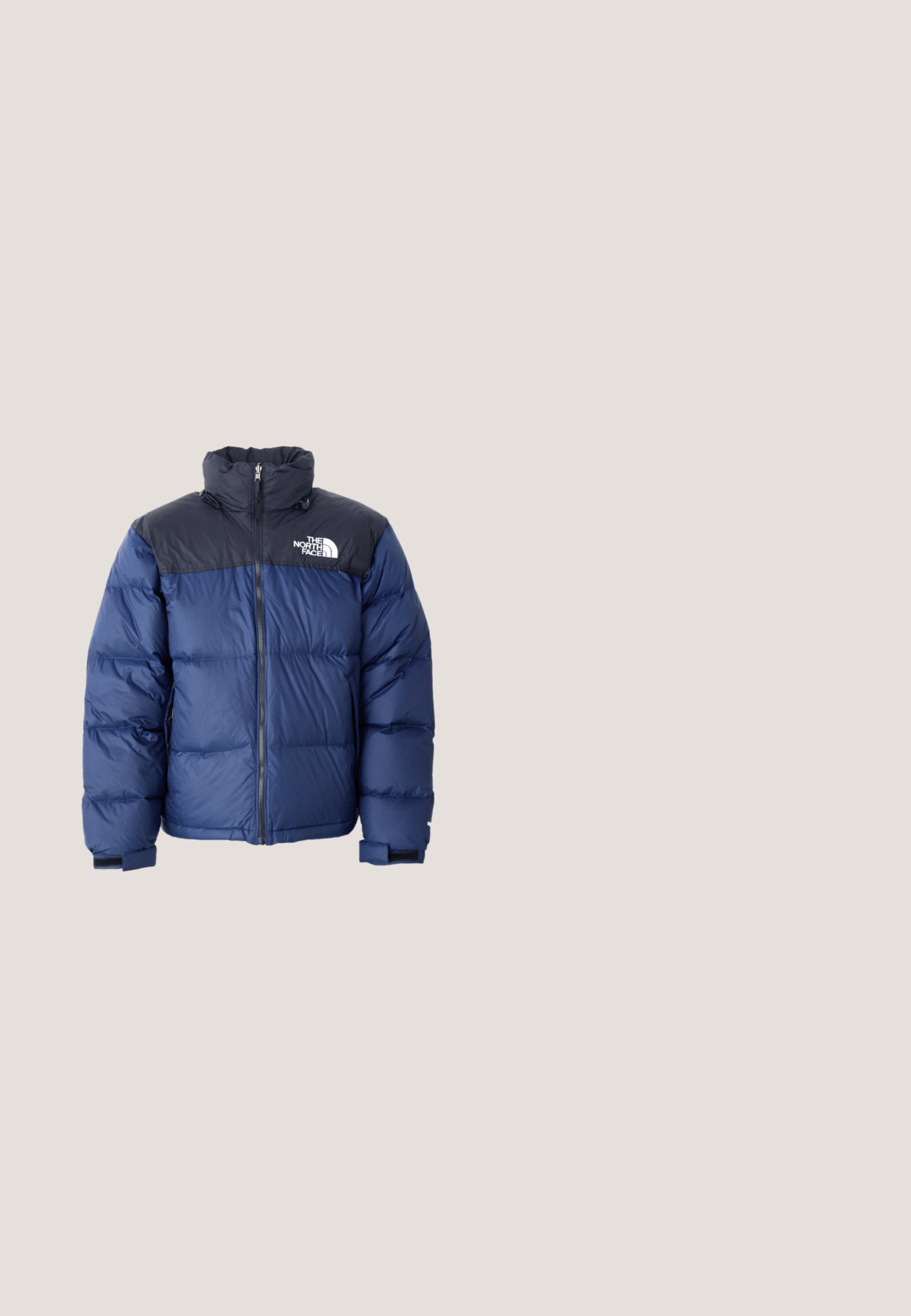 Mørkeblå pufferjakke med en sort topdel, høj krave, frontlynlås og logo på brystet. Føles bulky med elastiske manchetter.; Grå fleece-hættetrøje med frontlomme, justerbar snøre i hætten og et lille hvidt logo på venstre bryst.; Grå bomulds t-shirt med korte ærmer og rund halsudskæring, der har en lille sort firkantet logo på brystet med tekst nedenunder.; Sorte sweatpants lavet af blødt stof. Har en elastisk talje med snor, elastiske manchetter og et lille hvidt logo på låret.; Beige og sort vandrestøvle med elastiske snørebånd, struktureret stof og en spraglet hvid sål. Har et højt ankel-design for støtte.; Sort bæltetaske lavet af slidstærkt nylon med et stort hovedrum med lynlås og en frontlomme. Har en logo-patch og justerbar rem.