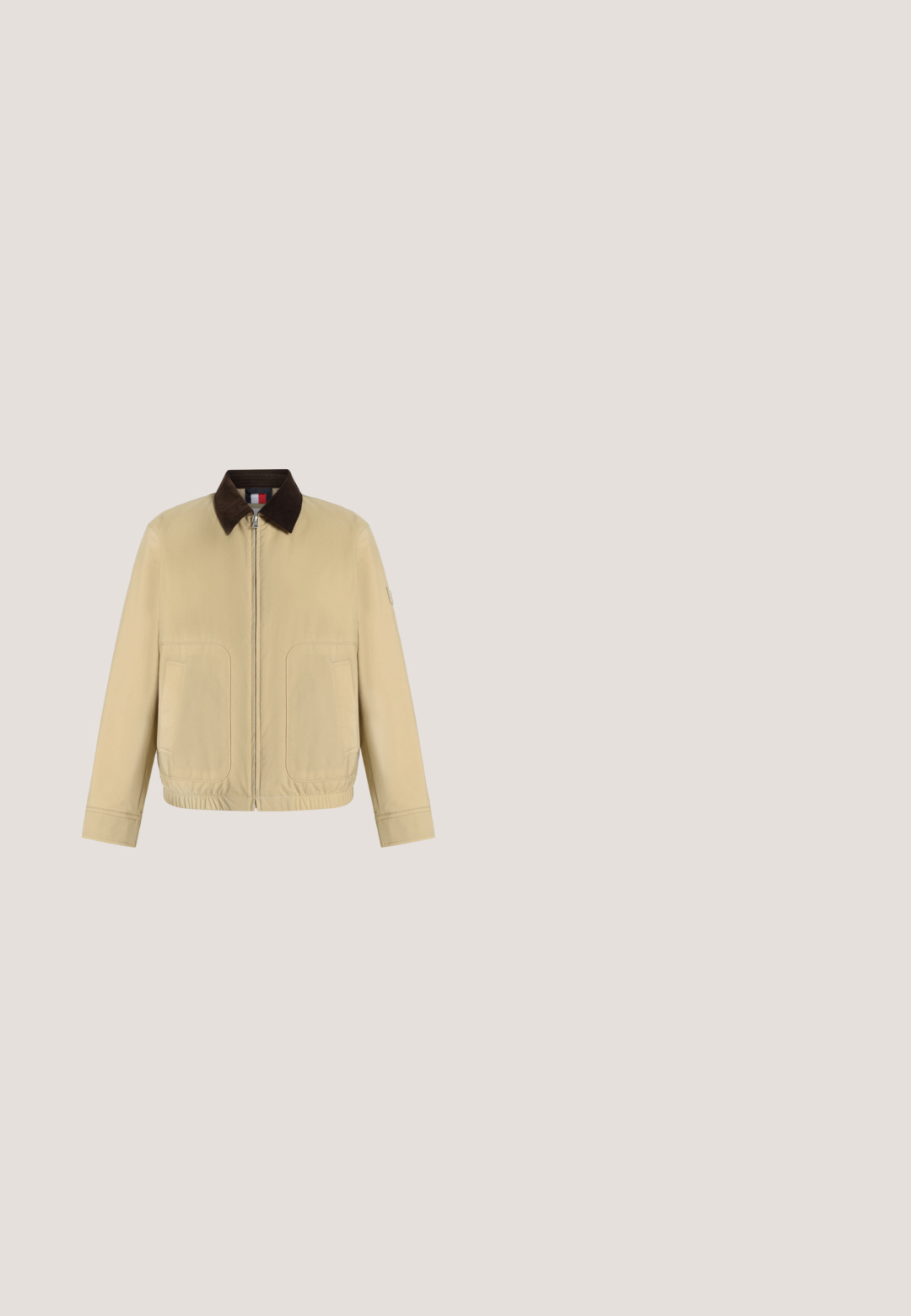 Veste beige avec fermeture éclair, col marron foncé, deux poches avant, manches longues et ourlet élastique, présentée sur un fond blanc uni.; Polo beige à manches courtes avec deux boutons et un logo brodé discret sur la poitrine gauche, présenté sur un fond uni.; Jean bleu foncé, coupe droite, avec poches avant, passants de ceinture et fermeture par bouton sur fond uni.; Botte de cheville en cuir marron avec une surface texturée, accents noirs, bout rond et semelle robuste, comportant six œillets pour les lacets.; Sac fourre-tout en toile blanche avec des accents bleu marine. Dispose de deux poignées robustes et d'un écusson logo à l'avant. Forme rectangulaire.; Bracelet en métal avec des maillons alternés argentés et noirs, doté d'un fermoir rectangulaire orné d'un logo rouge, blanc et bleu.