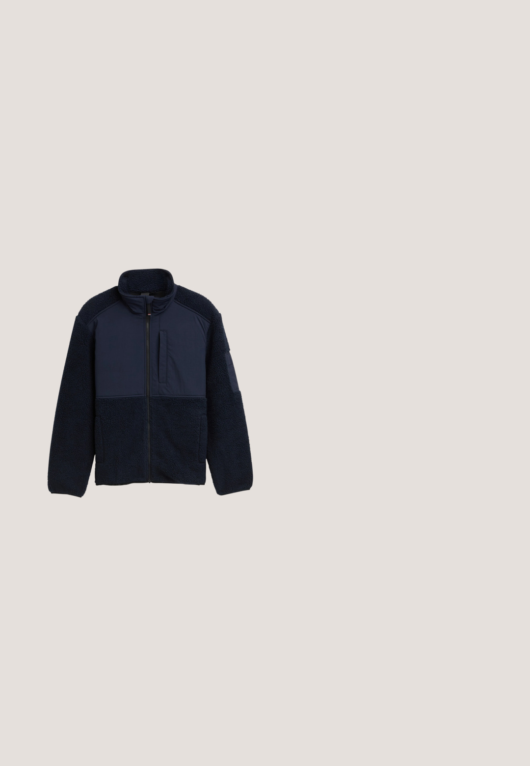 Marineblå fleecejakke med lynlås foran, høj krave og en kombination af tekstureret fleece og glatte stofpaneler. Inkluderer en brystlomme og sidelommer.; Marineblå langærmet t-shirt med rund hals og orange og hvid tekst: "ROOTED IN QLY COASTAL CREW TOM TAILOR 1962 ORIGINAL CUSTOM GOODS."; Mørkeblå denim flare jeans med mellemhøj talje, fem lommer og kontrastsyninger. Glat tekstur med minimal slid.; Brune og sorte ankelstøvler med en overdel i ruskind, tekstureret sort gummisål og snørebinding samt pelskant omkring kraven.; Navyblå rektangulære solbriller med mørke linser og røde accenter på stængerne, placeret på en hvid overflade.; Sort tekstureret crossbody taske med justerbar rem, med Tommy Hilfiger-logo og lille rød, hvid og blå flagdetalje.