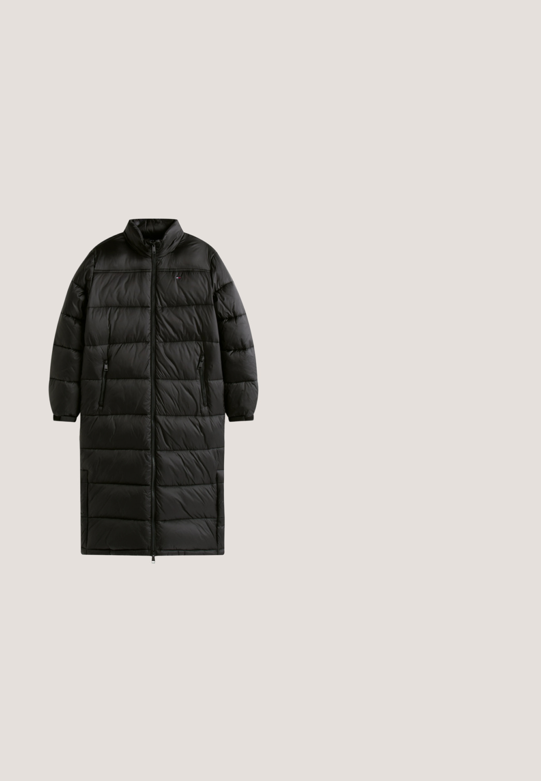 Long manteau d'hiver noir matelassé avec col montant, fermeture éclair devant, poches latérales zippées et manches longues.; Pull noir avec manches côtelées et col roulé. Comprend un patch logo à l'avant en bleu, rouge et blanc avec le texte « TOMMY JEANS ».; Jean en denim bleu avec poches avant, passants de ceinture, fermeture par bouton et coupe droite sur fond blanc.; Bottine en cuir noir au design épuré, à bout rond, avec des coutures texturées en haut et un talon bloc. Équipée d'une fermeture éclair et d'une tirette.; Sac fourre-tout en nylon rouge avec une large ouverture, des poignées courtes arborant le logo "TOMMY JEANS" et une texture lisse et résistant à l'eau.; Boucles d'oreilles en forme de cœur en ton or avec un centre découpé, surface texturée et détail de logo gravé. Fermeture à tige sécurisée.