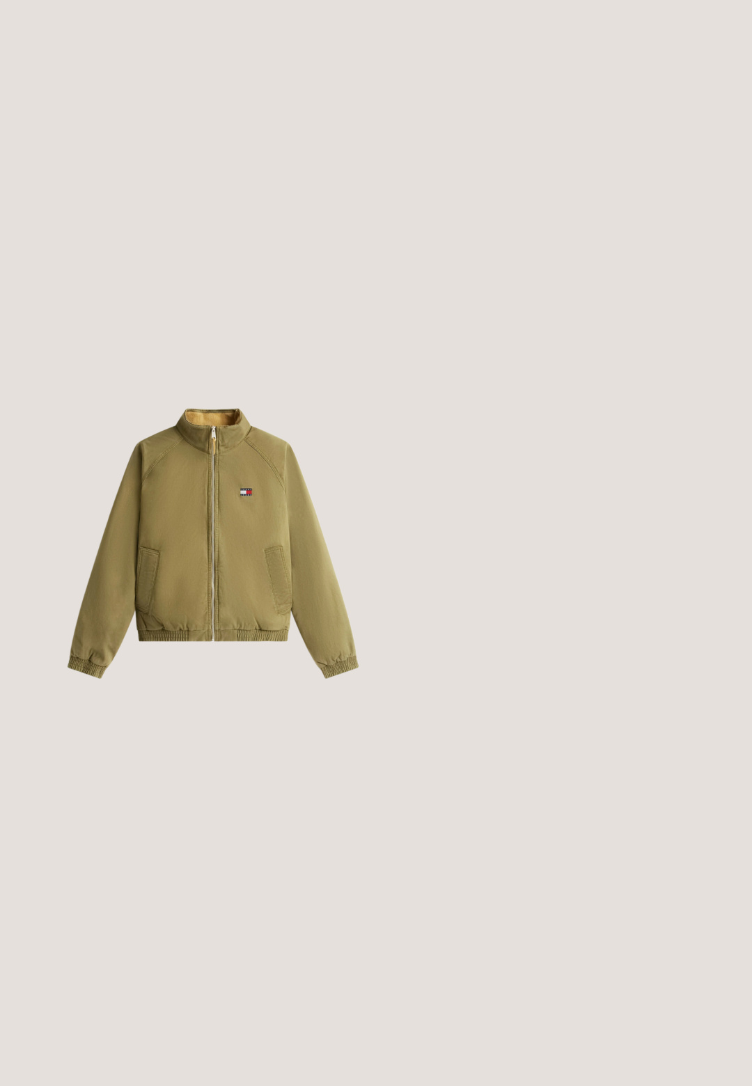 Hellolivgrüne Jacke mit Reißverschluss und Stehkragen, zwei Fronttaschen, elastischen Bündchen und Saum sowie einem kleinen rechteckigen Logo auf der Brust.; Cremefarbener Langarmstrickpullover mit Rundhalsausschnitt und kleinem Tommy Hilfiger Logo auf der linken Brust.; Schlichtes weißes Kurzarm-T-Shirt mit kleinem Tommy Jeans-Logo auf der linken Brust und rundem Ausschnitt.; Blaue Denim-Jeans mit weitem Bein, vorne mit Knopf- und Reißverschluss, Gürtelschlaufen und seitlichen Taschen, mit leichtem Verblassen an den Oberschenkeln.; Braune Leder-Ankle-Boots mit Metallösen, weißem Kunstfellfutter, schwarzem gepolstertem Kragen, robustem Sohlenprofil und geprägtem Logo an der Seite.; Schwarze Umhängetasche mit vertikalen roten, weißen und marineblauen Streifen und kleinem Tommy Hilfiger Logo, das nahe oben zentriert ist.