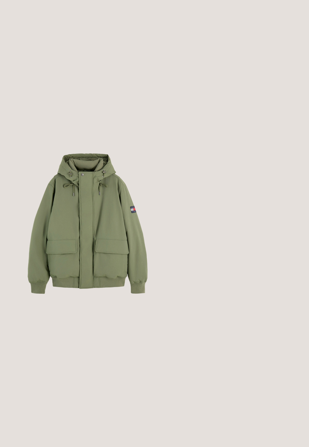 Chaqueta verde con capucha y cordones, bolsillos delanteros con solapa, puños y bajo acanalados, y un pequeño parche con logo en la manga izquierda.; Jersey de punto blanco de manga larga con el logo de la bandera de Tommy Hilfiger en rojo, blanco y azul y el texto "TOMMY HILFIGER SINCE 1985" en la parte delantera.; Camiseta de algodón beige claro con mangas cortas, escote redondo y un pequeño parche de logo en el pecho. Textura suave y corte relajado.; Pantalones chinos negros de algodón. Presentan un diseño de pernera estándar, bolsillos frontales y un cierre de botón con una textura suave.; Bota de tobillo negra de cuero con cordones, con un cuello acolchado gris oscuro y suela gruesa que presenta un detalle rojo, blanco y azul cerca del talón.; Bolso bandolera rectangular negro con franja texturizada, pequeño logotipo de Tommy Hilfiger y correa de hombro ajustable.
