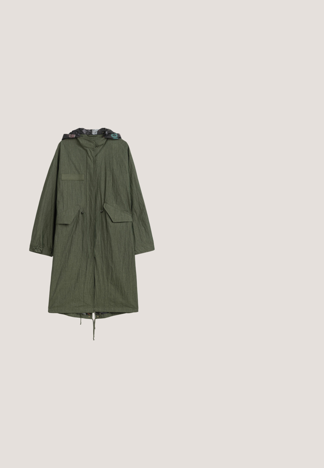Lange olijfgroene gewatteerde parka met capuchon, voorvakken met klep, verstelbare taillekoorden en een patroonvoering die zichtbaar is bij de capuchon.; Groene gebreide cardigan met ingewikkelde botanische en oogpatronen. Verkorte pasvorm met ribgebreide manchetten, ronde halslijn en koordsluiting in de taille.; Korte mouwen baseball-T-shirt met crèmekleurige body en contrasterende donkergroene mouwen en kraag, plat neergelegd op een witte achtergrond.; Wijdvallende broeken in een glanzend olijfgroene afwerking zijn voorzien van een contrasterende lichtere verticale streep, klassieke zakken en zilveren hardware accenten.; Groene suède sneakers met witte leren accenten, geprofileerde stiksels, vetersluiting aan de voorkant en rubberen zool. Bevat unieke ontwerpelementen langs de zijkanten.; Tas met camouflagepatroon, zacht en gewatteerd ontwerp, voorzien van een enkele verstelbare schouderband en een ritssluiting. Donkergroene tinten domineren.