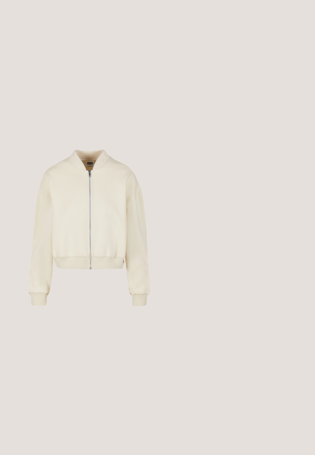 Chaqueta bomber de crema clara con cierre de cremallera, puños y dobladillo acanalados. Fabricada en material suave, con cuello redondeado y corte relajado.; Sudadera beige recortada hecha de una tela suave con detalles acanalados. Presenta una capucha y bordado en la parte frontal que dice "KARL KANI EST. 1989."; Top corto de punto beige con un escote redondeado, que presenta un gráfico ovalado negro en el centro con texto repetido.; Pantalones anchos de color crema con cintura elástica y bolsillos con solapa a cada lado, mostrados sobre un fondo blanco.; Zapatilla blanca de cuero con perforaciones, logo Nike en marrón y cordones. Cuenta con suela texturizada y cuello acolchado.; Pequeña bolsa acolchada blanca con cadena de plata, cierre de cremallera, logo circular y un pequeño llavero en forma de mono plateado.