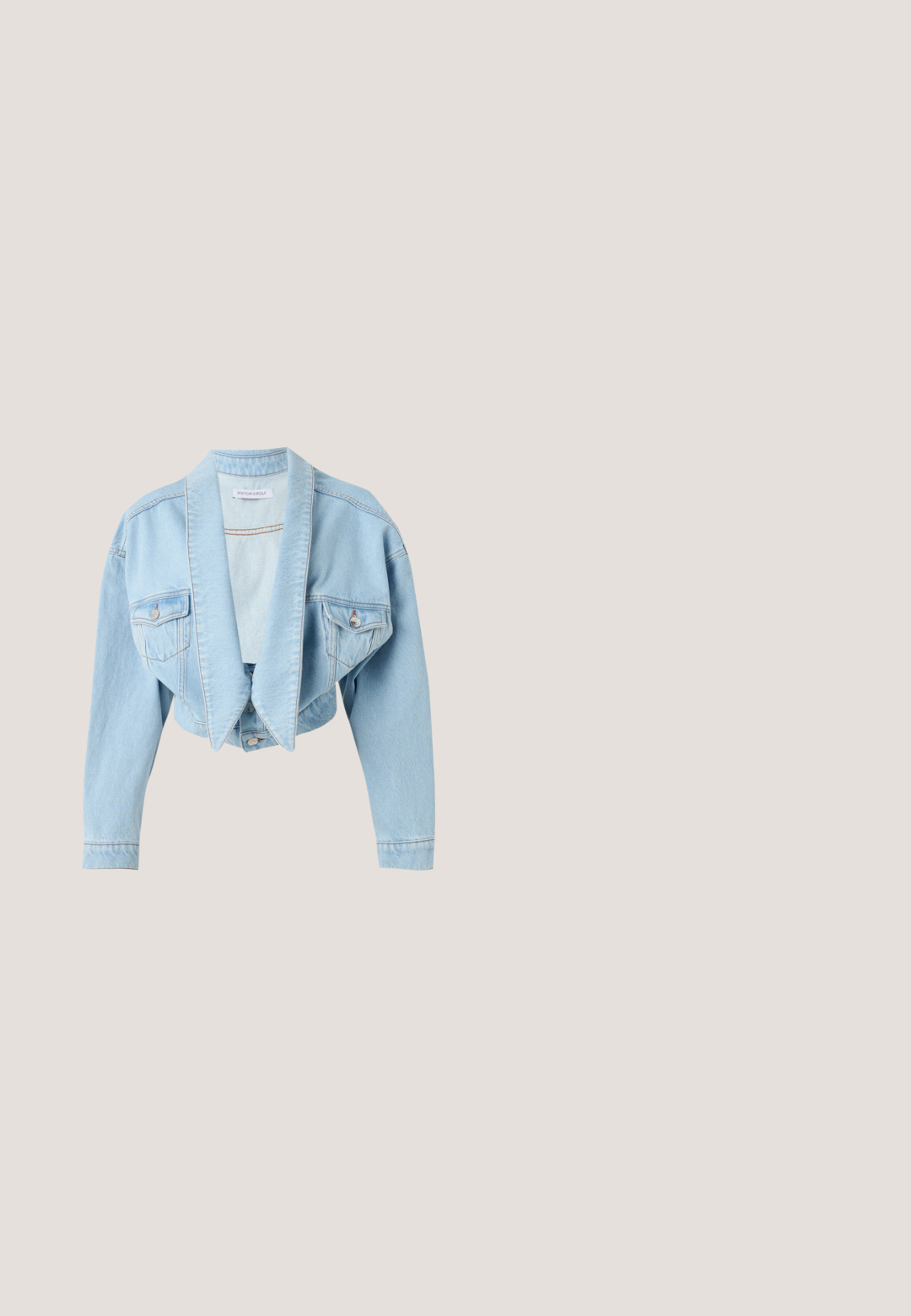 Lyseblå afkortet denimjakke med oversize slag, lukkede brystlommer med knapper og lange ærmer på en hvid baggrund.; Hvid ærmeløs kjole med rund halsudskæring, tætsiddende liv og bølgende skørt. Har lodrette sømme og en skjult lynlås bagpå.; Beige hælsandal med lav, udvidet hæl og rem i tåsandalstil på en hvid baggrund.; Sorte runde solbriller med mørke linser og tynde gyldne stel, der hviler på en hvid overflade, vinklet mod højre.; Beige læder håndtaske med rundt topgreb, aftagelig skulderrem og guldfarvet MK logo vedhæng på ensfarvet hvid baggrund.; To stjerneformede øreringe med teksturerede overflader og lyseblå og ferskenfarvede krystaller i midten, sat i en glitrende guldfarvet base.