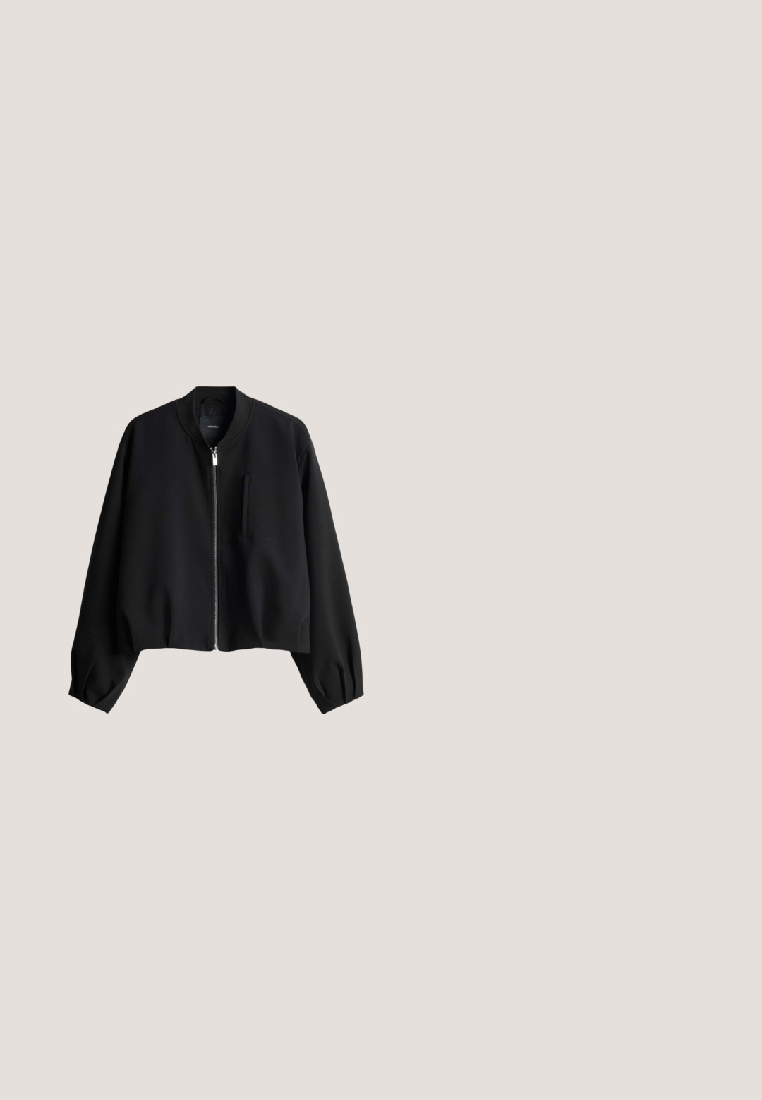 Zwarte bomberjack met een opstaande kraag, ritssluiting aan de voorkant, elastische manchetten en een borstzak. Gemaakt van gladde stof met een korte pasvorm.; Zwart T-shirt met ronde hals, opgerolde korte mouwen en klein geborduurd logo op de linkerborst, afgebeeld tegen een witte achtergrond.; Zwarte, wijde broek gemaakt van een gladde stof. Voorzien van een elastische tailleband en twee zakken aan de zijkant, met zichtbare stikdetails.; Zwarte instapschoen met een soepel leren bovenwerk, kurken middenzool en een ronde neus. Getextureerde rubberen buitenzool en minimalistisch ontwerp.; Zwarte geweven draagtas met afgeronde handvatten en een klein rechthoekig logo op het midden van de voorkant.; Zwarte metalen armband met een gedraaide middenontwerp, gladde uiteinden en een minimalistische, open vorm.