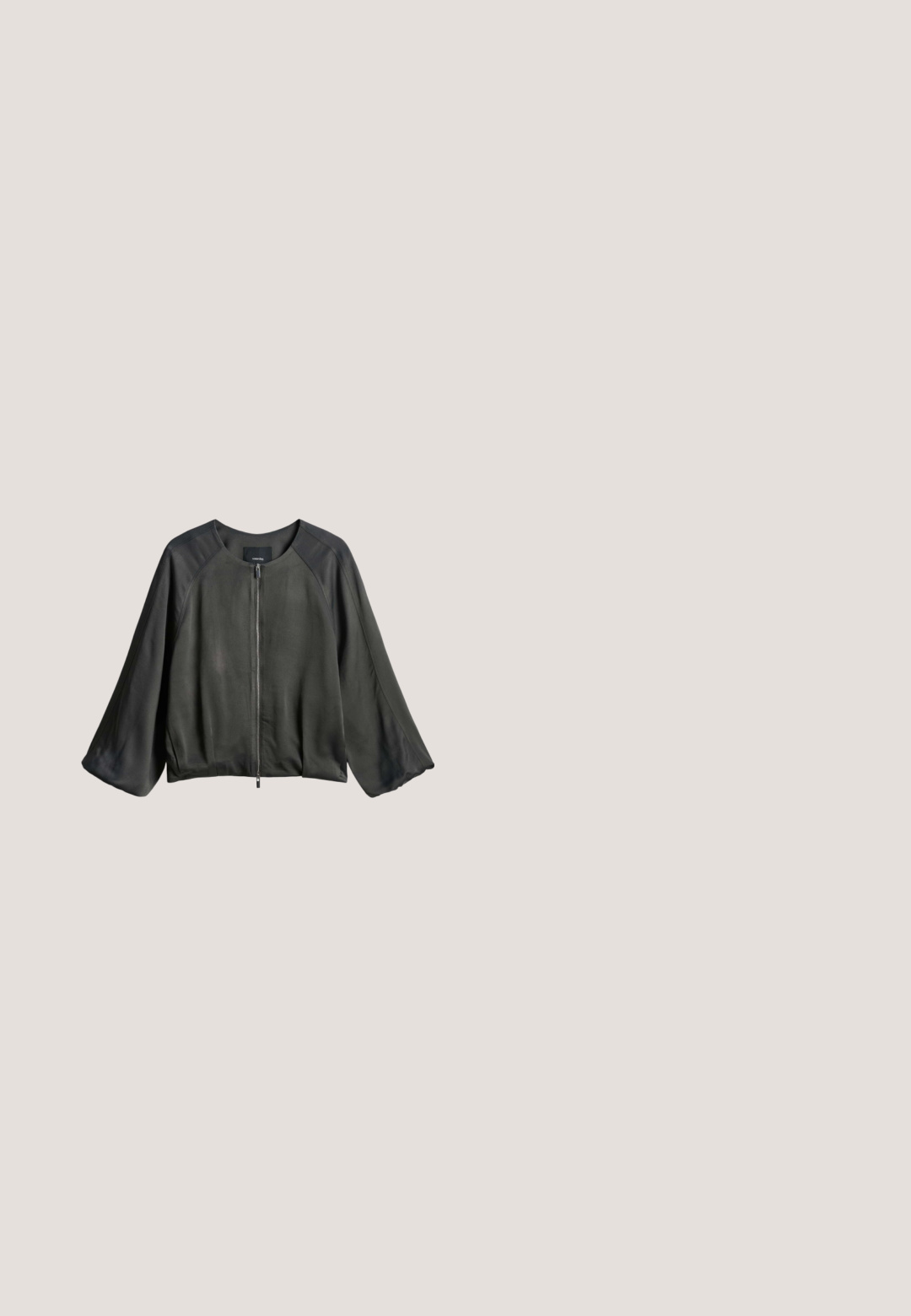 Zwarte lange mouwen jas met brede mouwen, ronde halslijn en voorste ritssluiting, plat gelegd op een witte achtergrond.; Korte mouwen, losvallende blouse in donkergrijs met een witte abstracte print. Zachte stof, ronde halslijn en zijsplitten aan de onderkant.; Pyjama broeken in een donkergrijze stof met een getextureerd groen abstract patroon. Voorzien van een elastische tailleband met een trekkoord voor aanpassing.; Zwarte leren loafer zonder achterkant met tassel-detail en lage hak, zij-aanzicht op een witte achtergrond.; Zwarte leren handtas met textuur, voorzien van twee bovenhandvatten en een verstelbare schouderriem met zilveren gesp.; Zwarte koordketting met een onregelmatige, glanzende zilverkleurige metalen hanger in het midden en een verstelbare knoop aan de bovenste uiteinden.