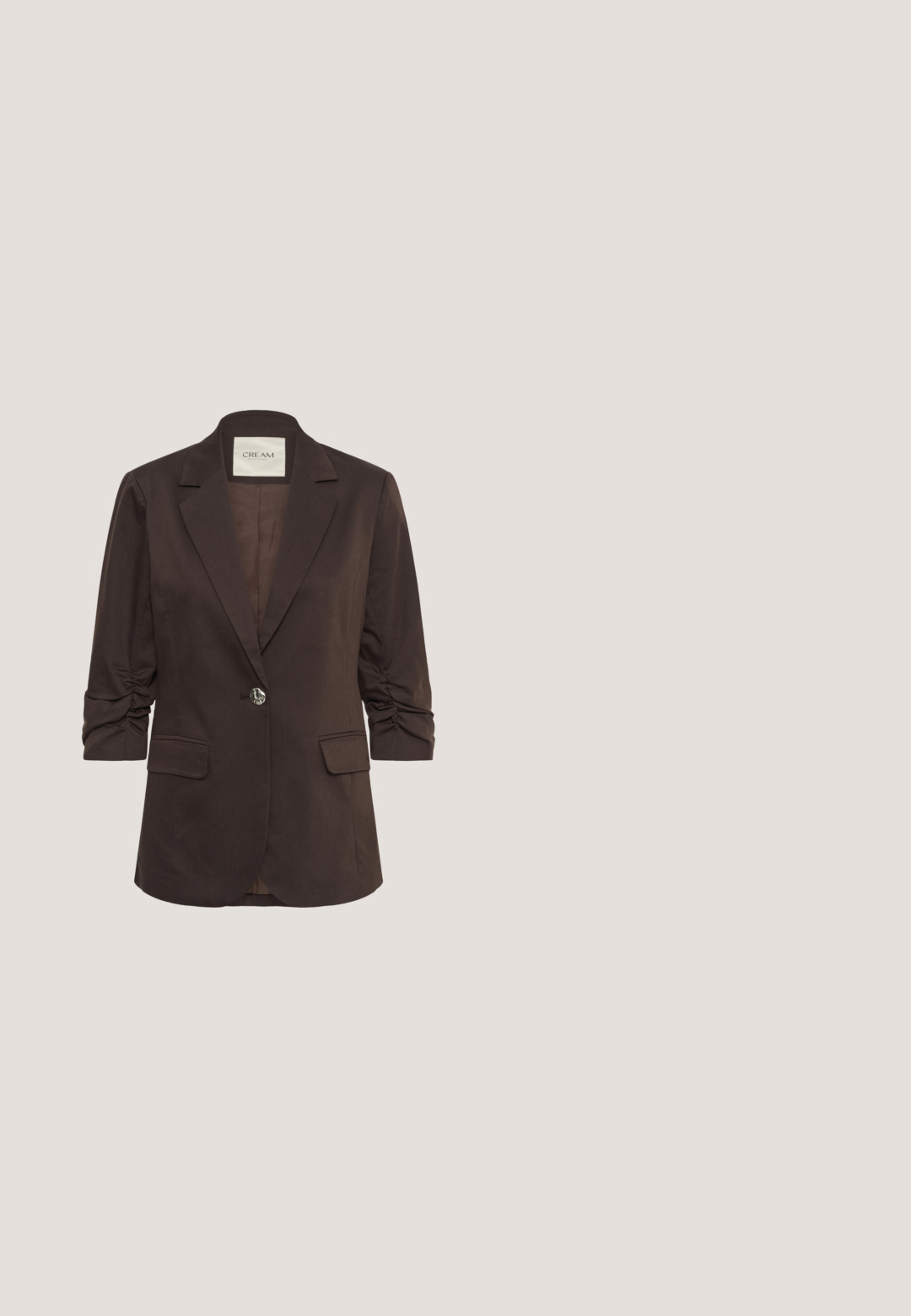 Donkerbruine damesblazer met gerimpelde driekwart mouwen, enkele zeshoekige knoopsluiting, nietkraag en klepzakken.; Bruine T-shirt met korte mouwen en ronde hals, met een klein "soaked" label aan de binnenkant van de achternek, effen en onopvallend.; Bruine op maat gemaakte broek van een textuurstof. Voorzien van een voorplooi, knoopsluiting en een rechte snit, ontworpen voor een slanke pasvorm.; Zijaanzicht van een bruine en beige sneaker met gemengde materialen waaronder suède, leer en nepbont, met een dikke off-white zool.; Donkerbruine gestructureerde lederen schoudertas met verstelbare riem, zilveren gesp, ritssluiting en klein merklabel bevestigd.; Stevige doorschijnende harsring in amberkleur met golvende patronen en een brede band tegen een witte achtergrond.