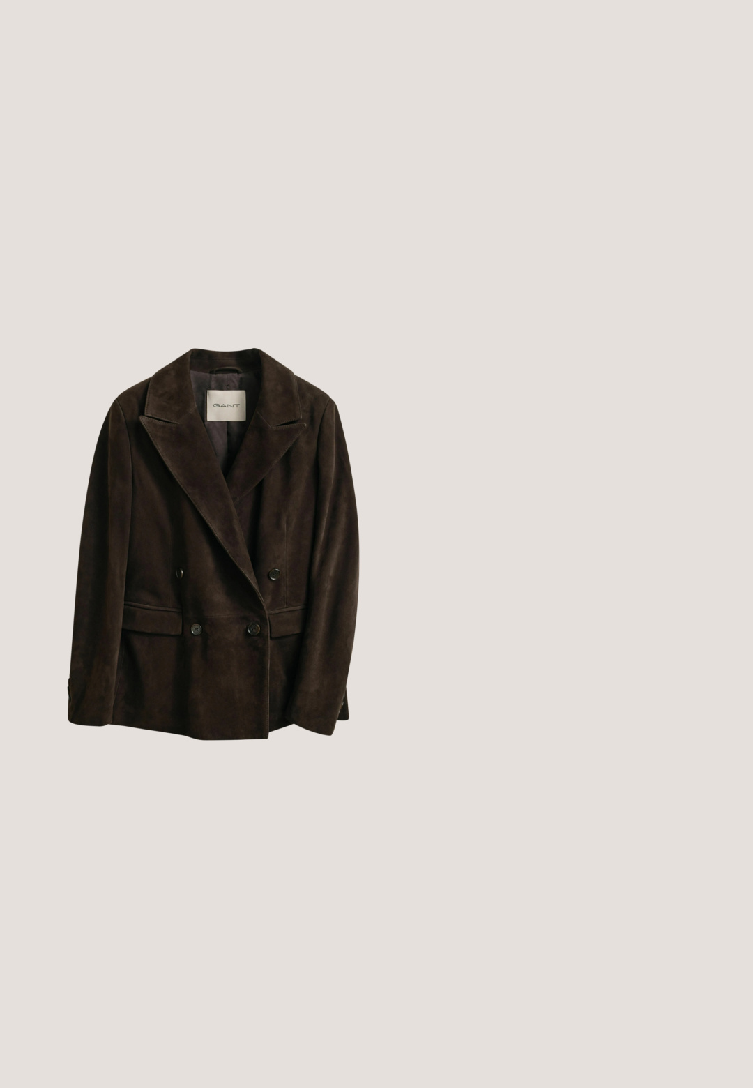 Donkerbruine suède dubbelzijdige blazer met klepkragen, vier knopen aan de voorkant en klepzakken, met het label GANT aan de binnenkant van de kraag.; Blauw denim overhemd met lange mouwen, spitse kraag, knoopsluiting aan de voorkant, twee borstzakken met knoopflappen en uitlopende manchetdetails.; Blauwe denim jeans met een hoge taille, brede wijde pijpen, voorvakken met inzetstukken, riemlussen en een knoopsluiting.; Bruine suède cowboylaars met een hoge schacht, puntige neus en subtiele witte stiksels. Bevat een gemusterde accent nabij de hak en een gestapelde houten hak.; Rode zijden sjaal met een witte hartomtrek, het woord "Coach" in schrift, een grafische afbeelding van een gevleugeld paard en de tekst "America's Original House of Leather."; Bruine leren riem opgerold met sierlijke antieke goudkleurige gesp, lus en uiteinde met bloemen- en geometrische gravures, op een witte achtergrond.