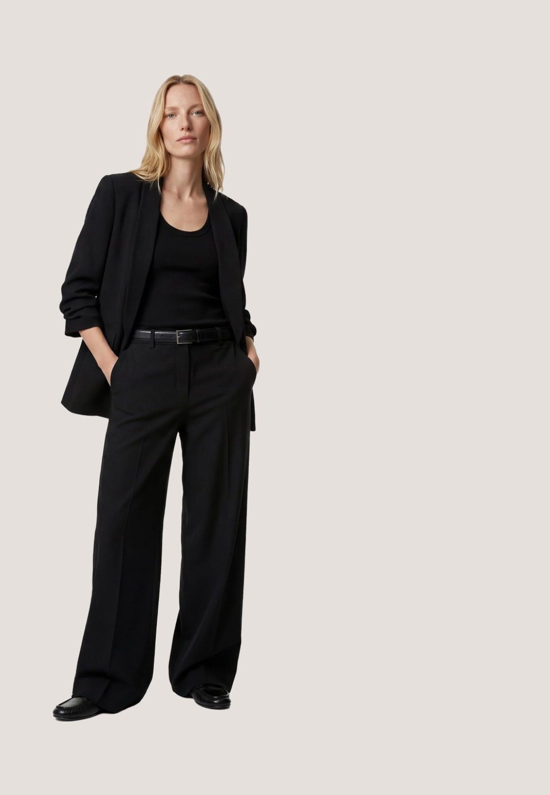 Zwarte blazer met sjaalkraag, lange mouwen met lichte plooien, twee voorzakken met klep en een gladde binnenvoering, plat gelegd op een witte achtergrond.; Zwart haltertopje met witte polkadots en een striksluiting bij de hals, aangesloten in de taille.; Zwarte broek met hoge taille, voorplooien en knoopdetails bij de tailleband, model met wijde pijpen, geen zichtbare zakken.; Zwarte gepatineerde leren slingback pump met een spitse neus, uitsparingen aan de zijkanten, een verstelbare enkelband en een dunne, slanke hak.; Zwarte clutch van krokodillenleer met zilveren kettingriem en metalen logoplaatje aan de voorkant, schuine aanzicht op witte achtergrond.; Zwarte satijnen scrunchie met een rafelige textuur en een gouden logo label. Cirkelvormig, zachte oppervlakte, geschikt voor het vastzetten van haar.