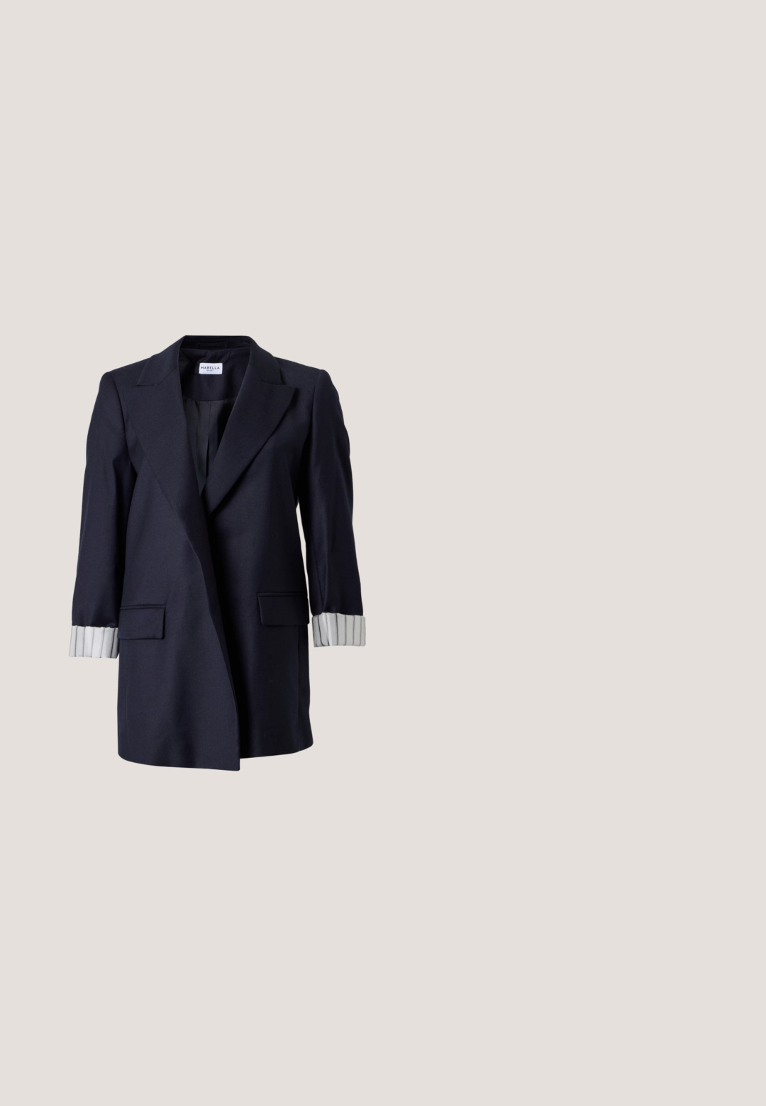 Marineblå blazer med hakkede revers, to forlommelommer med klap og hvide stribede manchetter, der er opbukket på lange ærmer.; Ærmeløs top i mørk marineblå satin med høj krave og åbning med knaplukning på ryggen. Glat tekstur med en let afslappet pasform.; Marineblå høj-lav nederdel med plisseringer og et diskret mønster af kortsymboler i en let skinnende stof.; Sort laklæder pumps med høje hæle, spids snude og stilethæl, vist i sideprofil på en ensfarvet hvid baggrund.; Blød navyblå læderhåndtaske med sølv lukning, enkelt skulderrem og aftagelig kæde til håndleddet på hvid baggrund.; Sølvfarvede chandelier øreringe med firkantede studs, runde perler og hængende kæde-strenge der ender i dråbeformede charms.