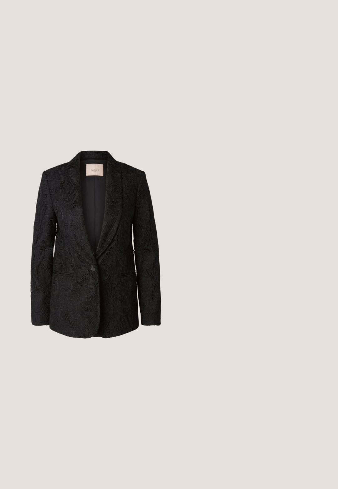 Blazer negro con un intrincado patrón de encaje, cierre de un solo botón, solapas con muesca y dos bolsillos frontales. Interior sin forro, ajuste moderno y entallado.; Camisa de botones en mezcla de seda, con una base negra que presenta un patrón abstracto de hojas en verde y rosa. Mangas abullonadas con puños elásticos.; Pantalones negros de pernera ancha hechos de tela suave, con pliegues frontales, cremallera y diseño clásico de cinturilla.; Sandalia de cuero negro con tiras trenzadas y tacón bajo tipo kitten, presentada sobre un fondo difuminado de color gris oscuro.; Bolso negro con textura de cocodrilo, borde superior fruncido, asa recogida y cordones con borlas en cada lado sobre un fondo blanco.; Pendientes circulares de oro con dos pequeños anillos de plata en cada uno, que muestran detalles sutiles del nombre de la marca grabado, colocados sobre un fondo blanco.
