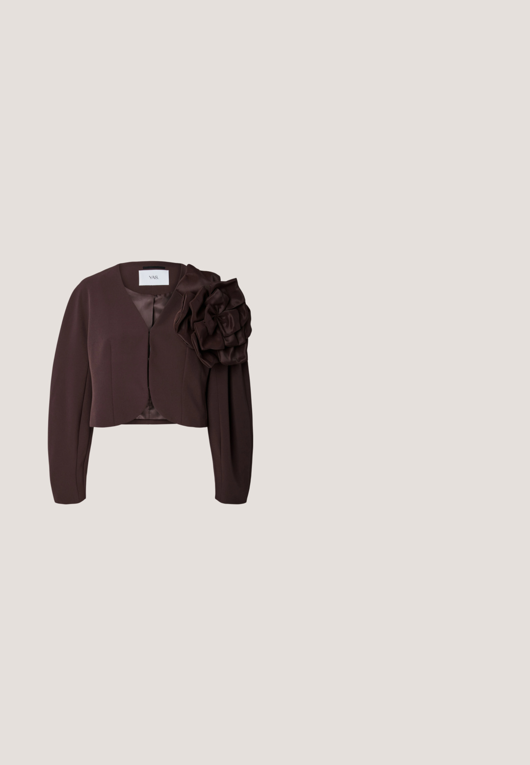 Dunkelbrauner, kurz geschnittener Blazer mit langen Ärmeln und einer großen dekorativen Stoffblume auf der rechten Schulter vor weißem Hintergrund.; Braunes, figurbetontes Langarmoberteil mit drapiertem Wasserfallausschnitt und gerafften Details an Taille und Ärmelsäumen.; Braune Weitbein-Hosen mit Wickeldesign, aus einem glatten, leichten Stoff gefertigt. Mit einem gefältelten Bund und einer fließenden Silhouette.; Brauner Kunstleder-Stiefelette mit spitz zulaufender Zehenpartie und Blockabsatz. Glatte Textur, Obermaterial mit elegantem Design und Lasche hinten.; Schwarze Schultertasche mit langem verstellbarem Riemen und strukturiertem Klappverschluss, aus weichem, pelzartigem Material.; Feine Goldkette mit kleinen, blumenförmigen Anhängern, gleichmäßig verteilt, und einem vertikalen Anhänger mit drei Blumenanhängern.